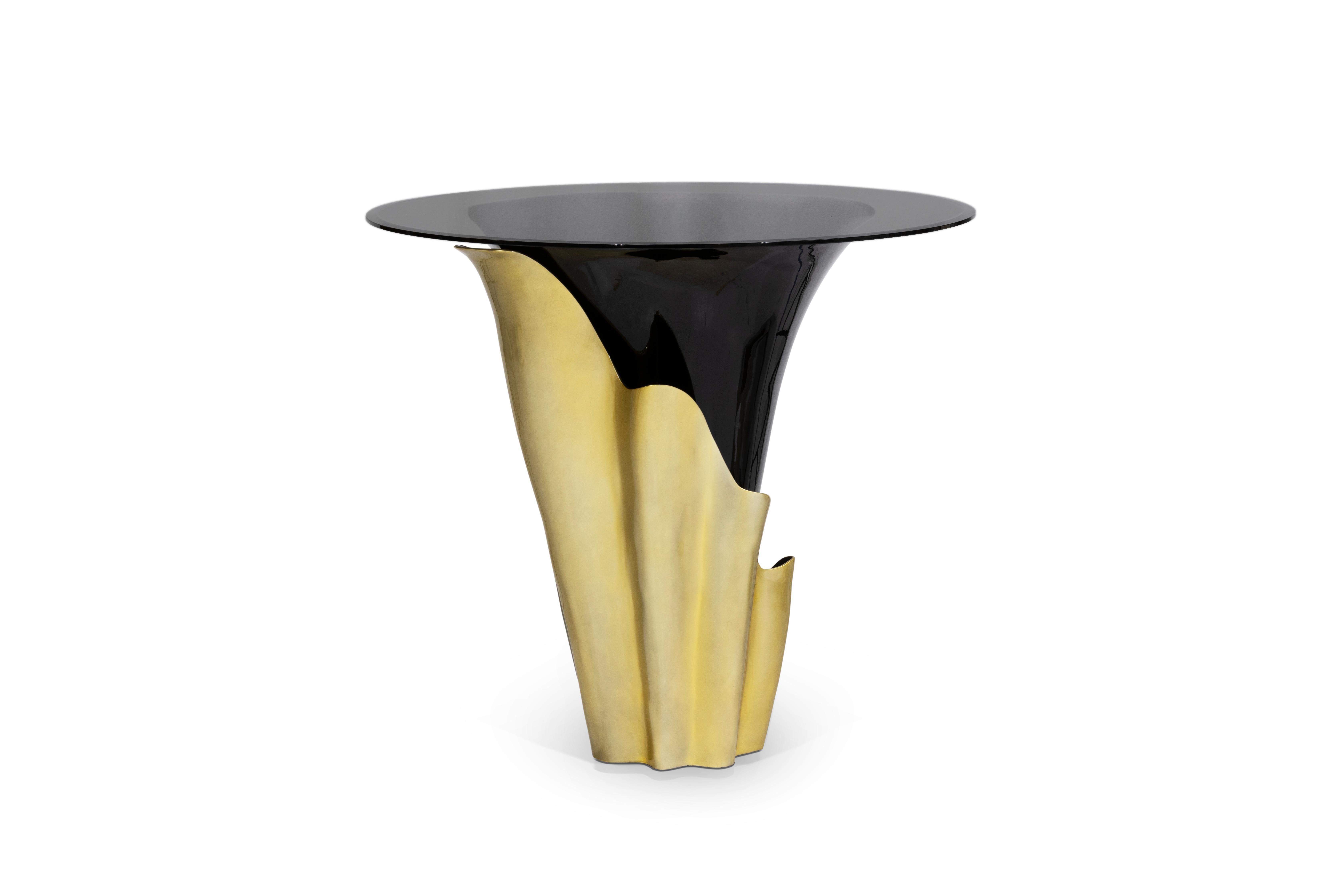 A central piece to any space, the contemporary design of the Yasmine table will have everyone doing double takes. The sultry silhouette is fashioned from tailored glass and mounted on a solid wooden base. Classic lacquer and luxurious plated
