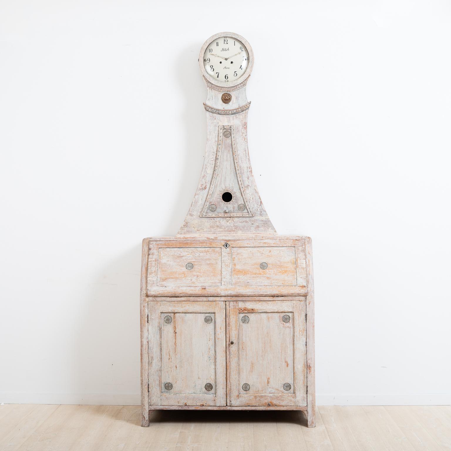 Swedish clock cabinet and bureau in Gustavian style. Manufactured in northern Sweden, circa 1800. The clock cabinet has round decorations. The surface has been dry scraped to original paint. The clock cabinet is divided into three parts. The cabinet