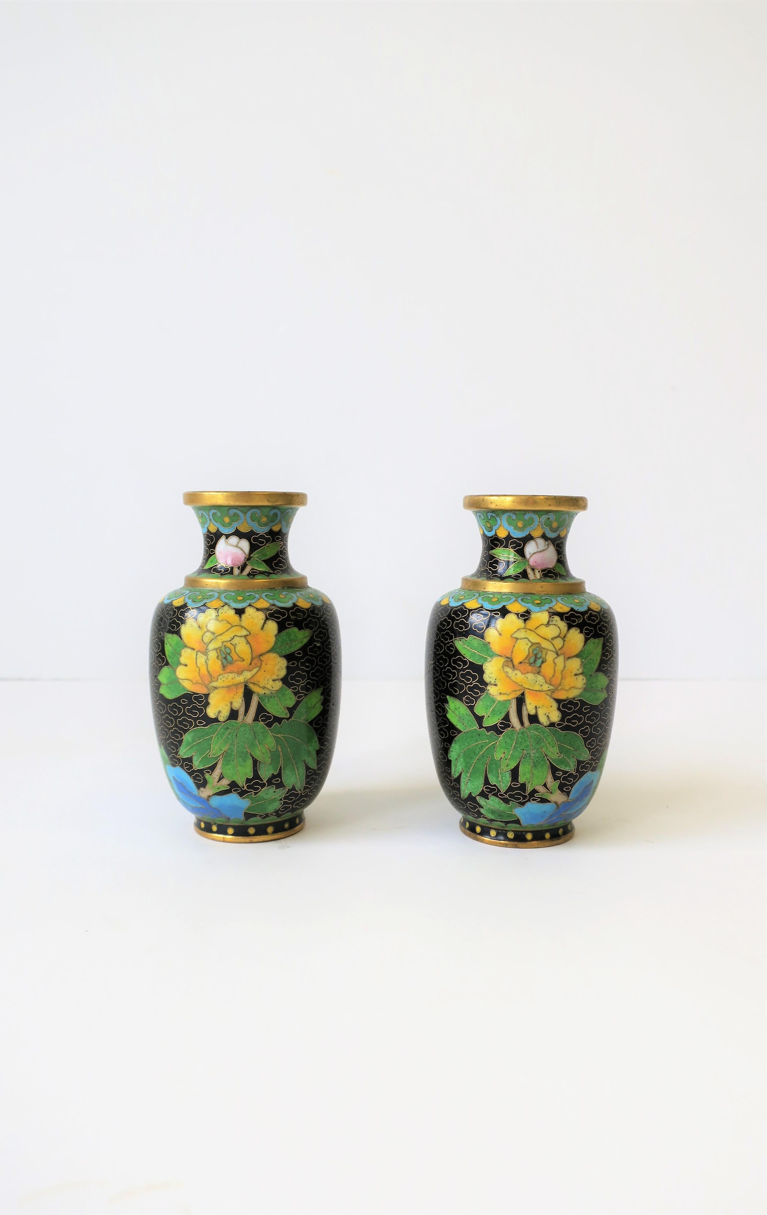 A beautiful pair of vintage yellow, black and green Asian Cloisonné enamel and brass vases, circa early to mid- 20th century, China. Vases have a yellow enamel flower and green leaf design with a black background. Other colors include white, blue,