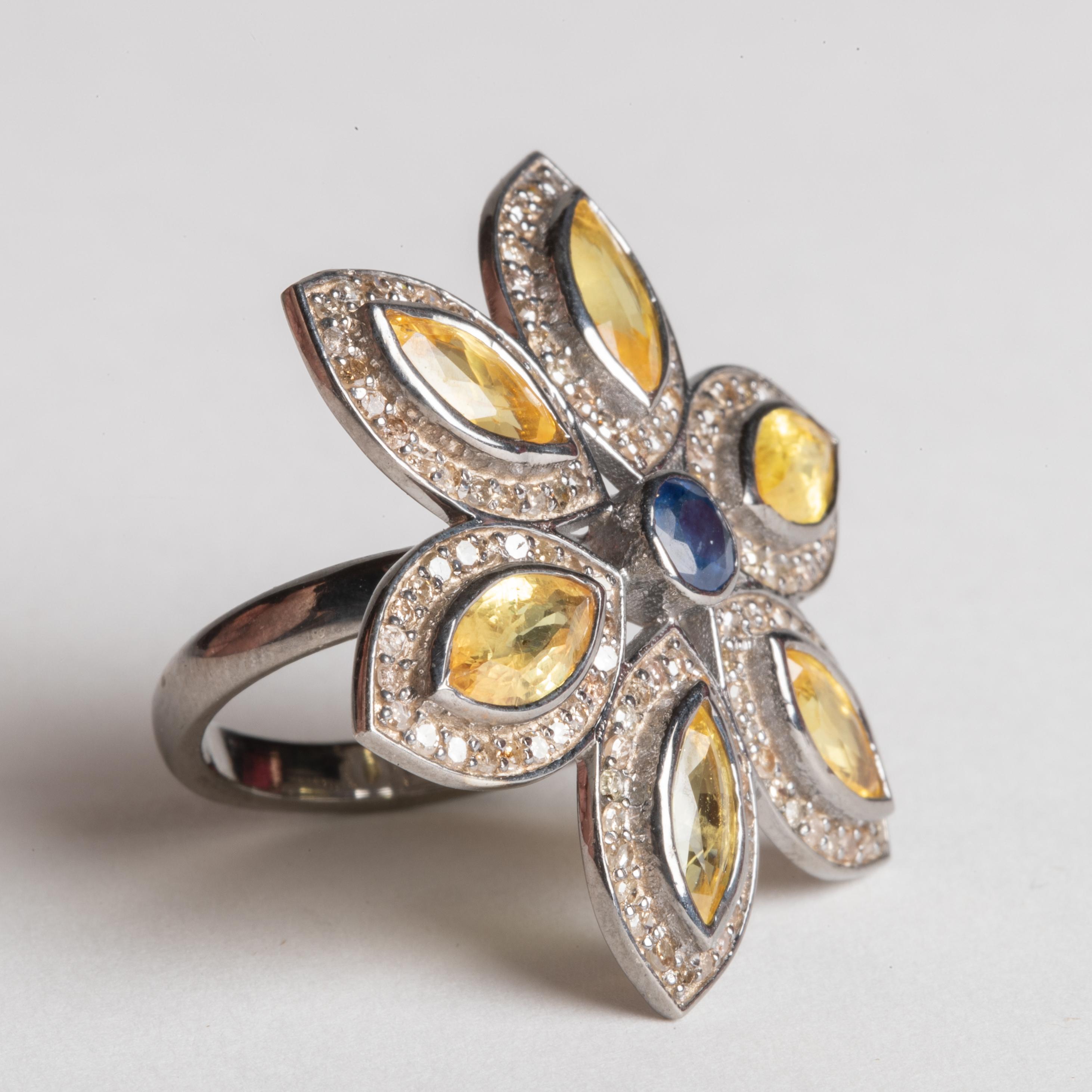 How fabulous is this.  A flower petal cocktail ring comprised of marquise cut yellow sapphires bordered in pave`-set, round brilliant cut diamonds with a faceted round blue sapphire at the center.  Set in sterling silver.  Sapphires total 4.45