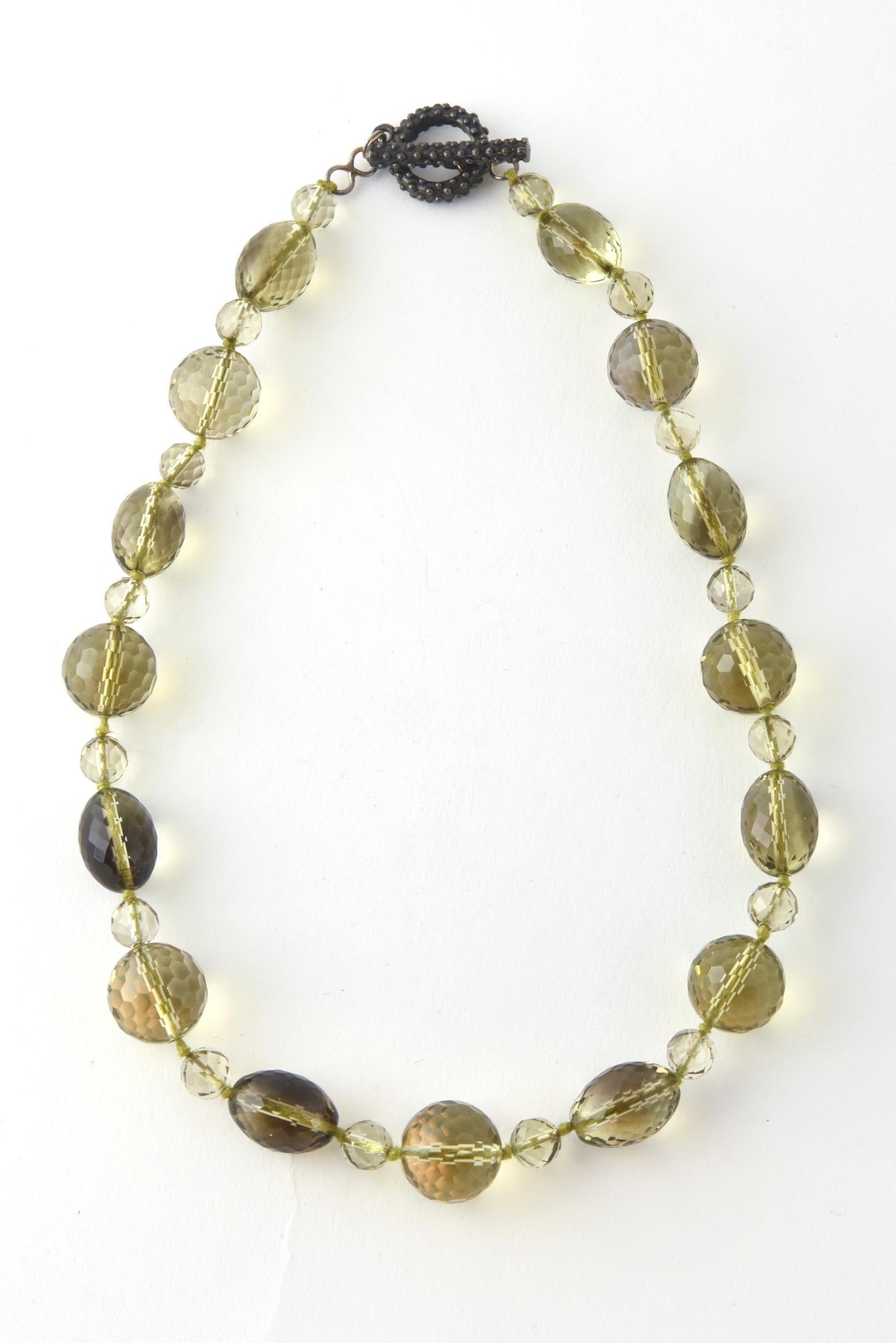 Necklace of faceted glass beads in shades of brown and yellow. Knotted between each bead. Beaded toggle closure with a blackened silver finish.