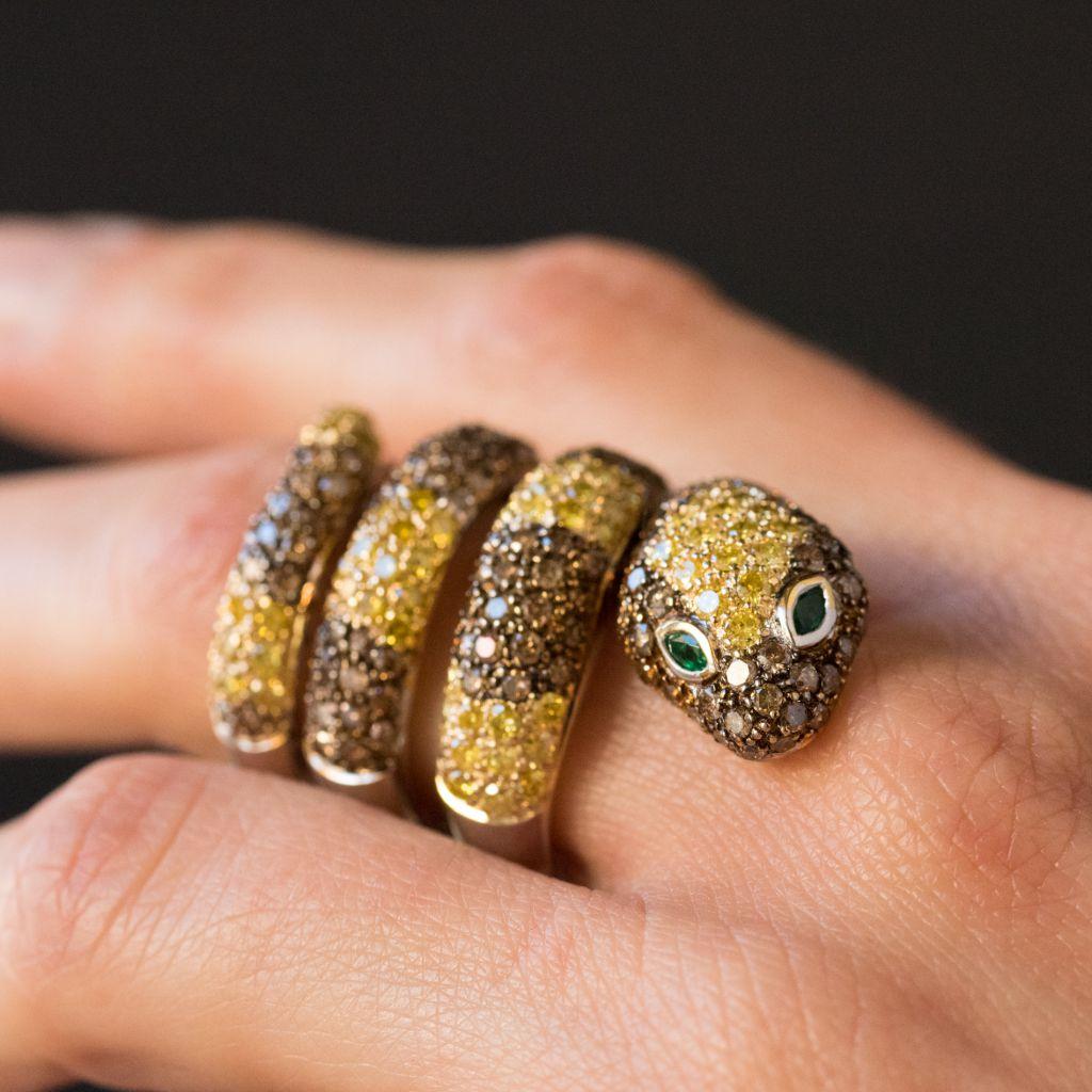 Ring in 18 carat white gold, eagle head hallmark. 

Featuring a coiled snake, this ring is set over half its surface with yellow and cognac diamonds that represent the scales. The eyes are emeralds. 

Total diamond weight: envion 5 carats tw emerald