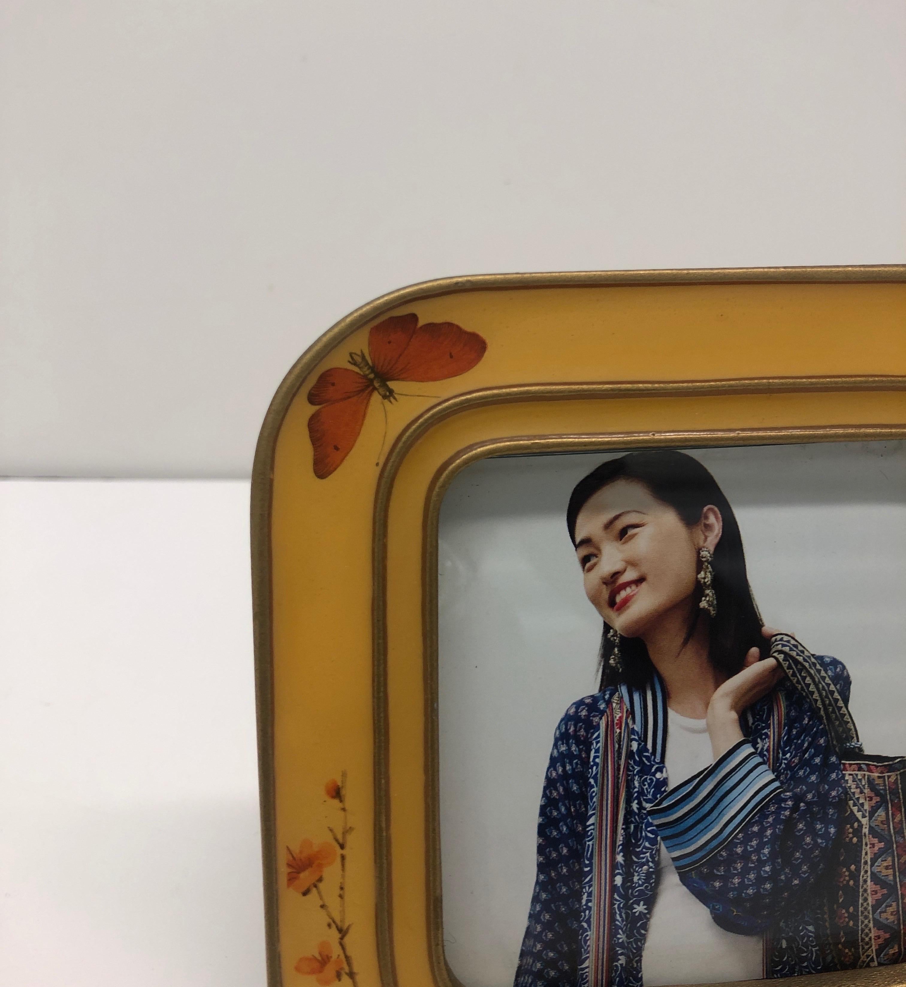 Yellow and orange enameled square decorative picture frame.
Butterflies and cherry blossom.
Wood back and stand.
Size: 5” H x 5” W x .25” D.