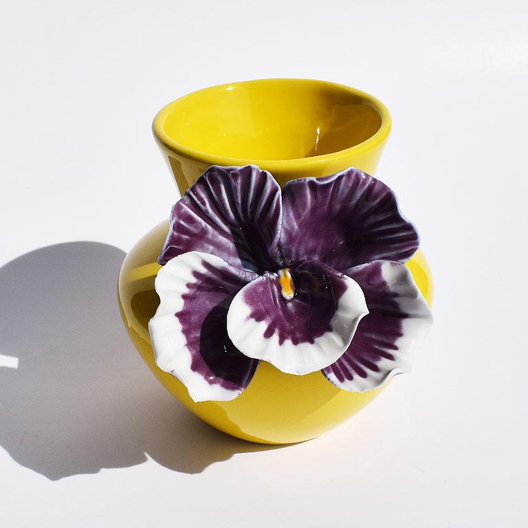 Bold colorful and sculptural yellow ceramic vase with bright purple orchid decoration. Urn shape in form, this Spring inspired vase is glazed in a bright yellow hue. Affixed to the side, is an eye catching bright purple orchid flower. It’s purple