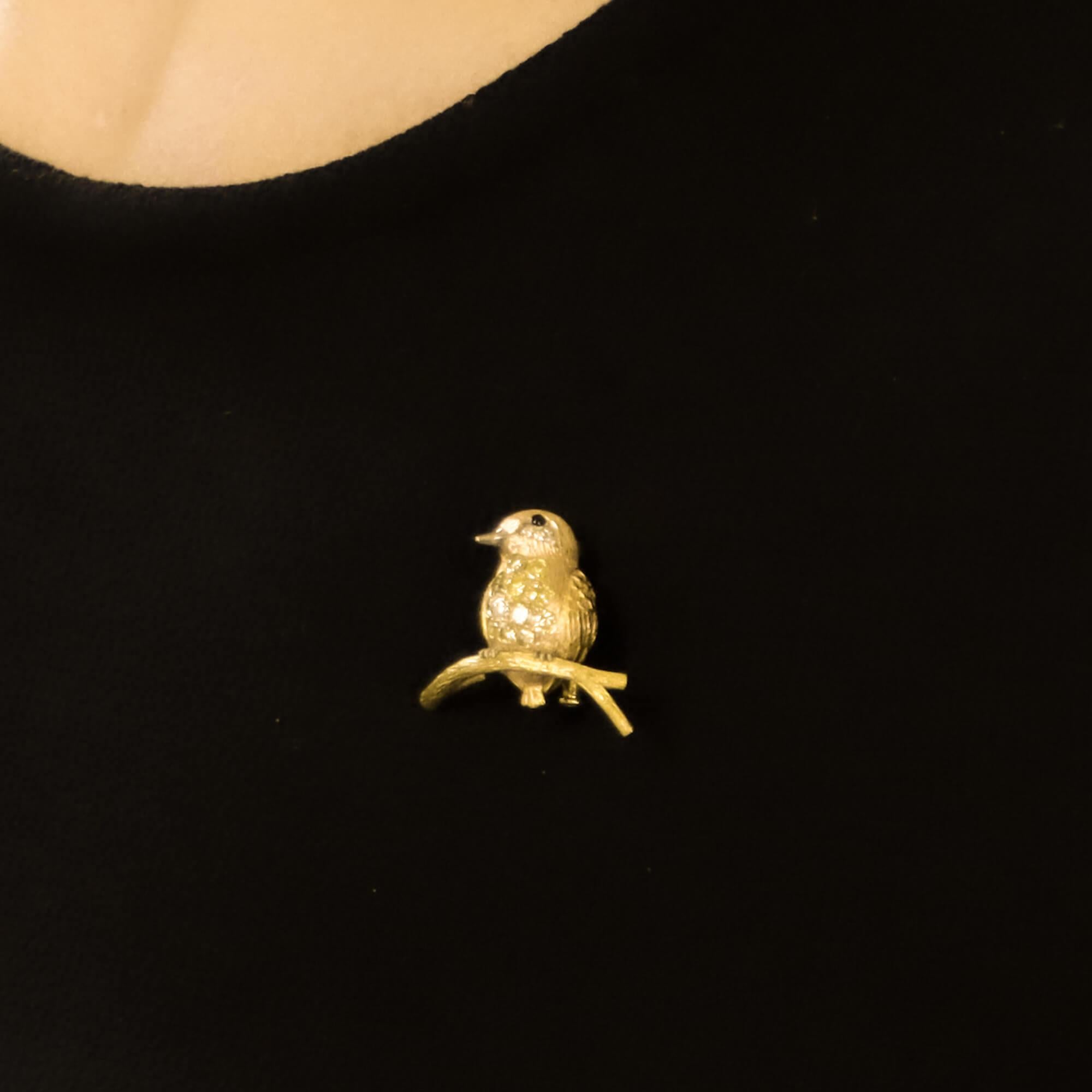 A beautiful yellow and white diamond bird pin brooch set in 18k yellow and rose gold.

The brooch depicts a sweet bird perched on a tree branch and is pavé throughout on the chest with 12 varying sizes of white and yellow round brilliant cut