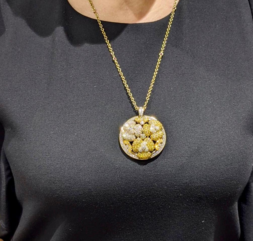 A Large 18k yellow gold diamond pendant. The circular pendant features a floral design of white and yellow diamonds. The white diamonds have an approximate weight of 4.78ct and the yellow diamonds total approximately 5.65ct. The pendant measures