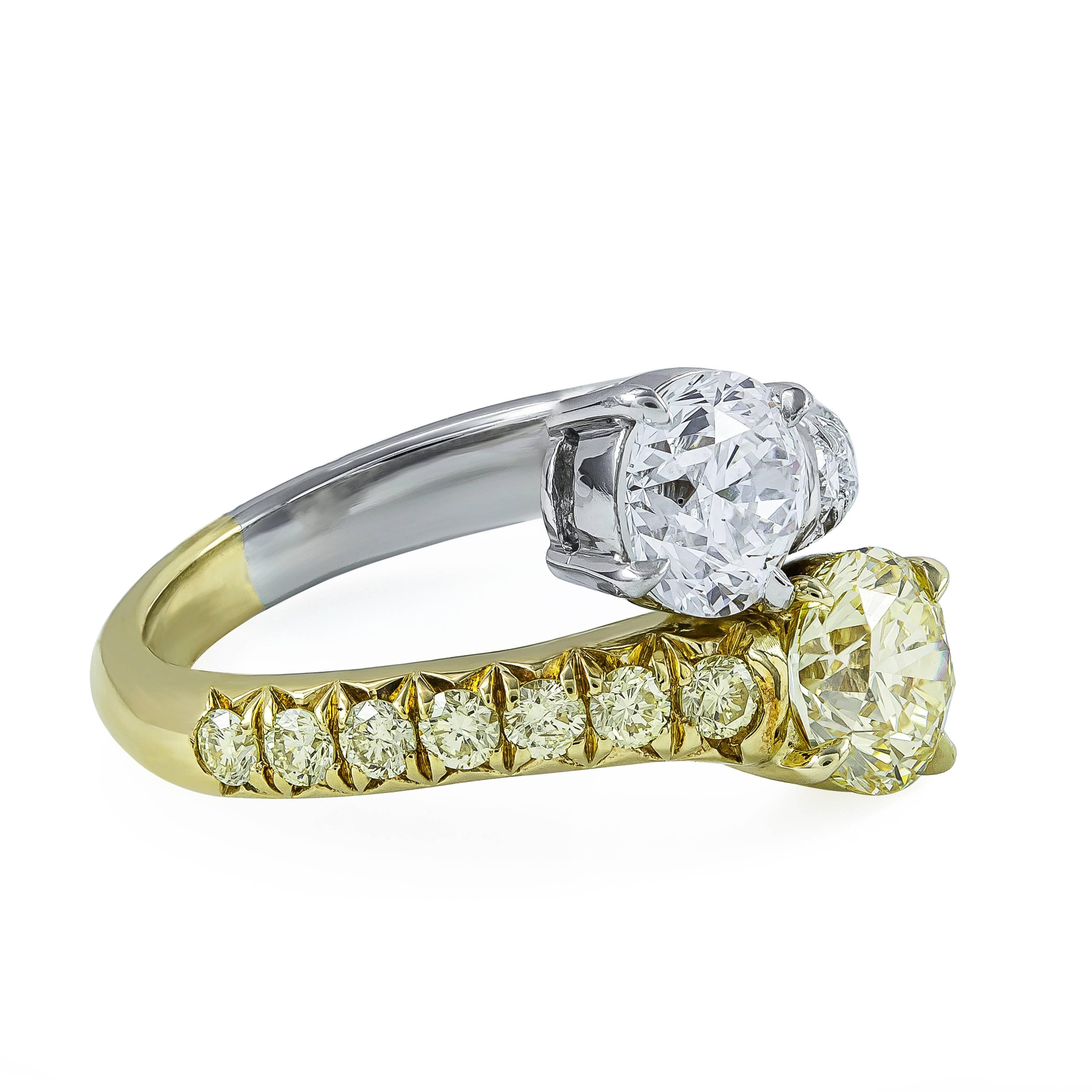 A very chic bypass engagement ring, showcasing two GIA certified round brilliant cut diamonds: a 1.01 carats with Fancy Light Yellow color and VS2 clarity and a 1.00 carat with D color and SI3 clarity, both set on a four prong setting. Accented by