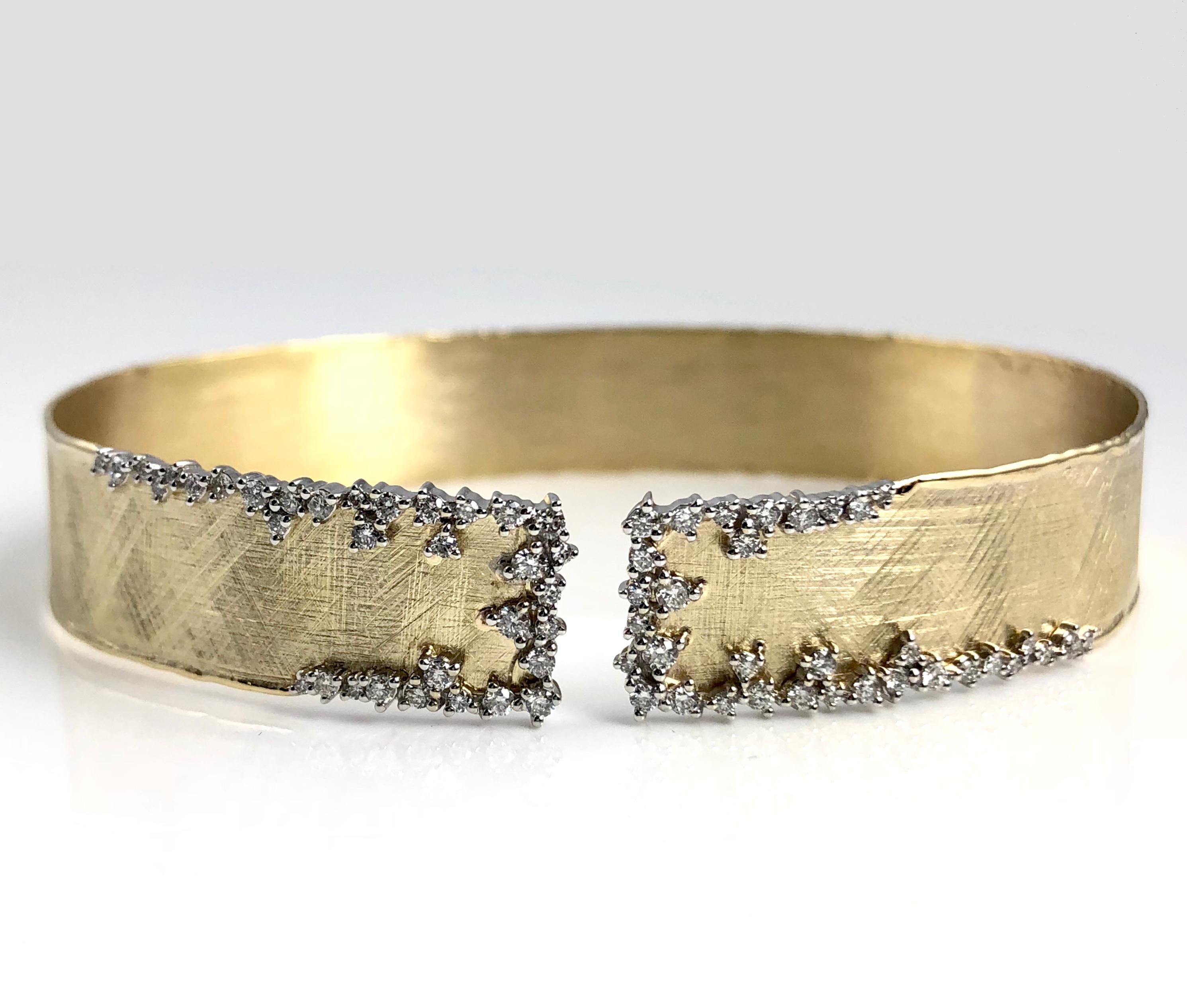 (DiamondTown) This rustic bangle has a brushed yellow gold design, accented by a delicate frost of round white diamonds at the opening. The bangle is flexible enough to pass over the hand, without any hinge or buckle.

The bangle is set in 14k