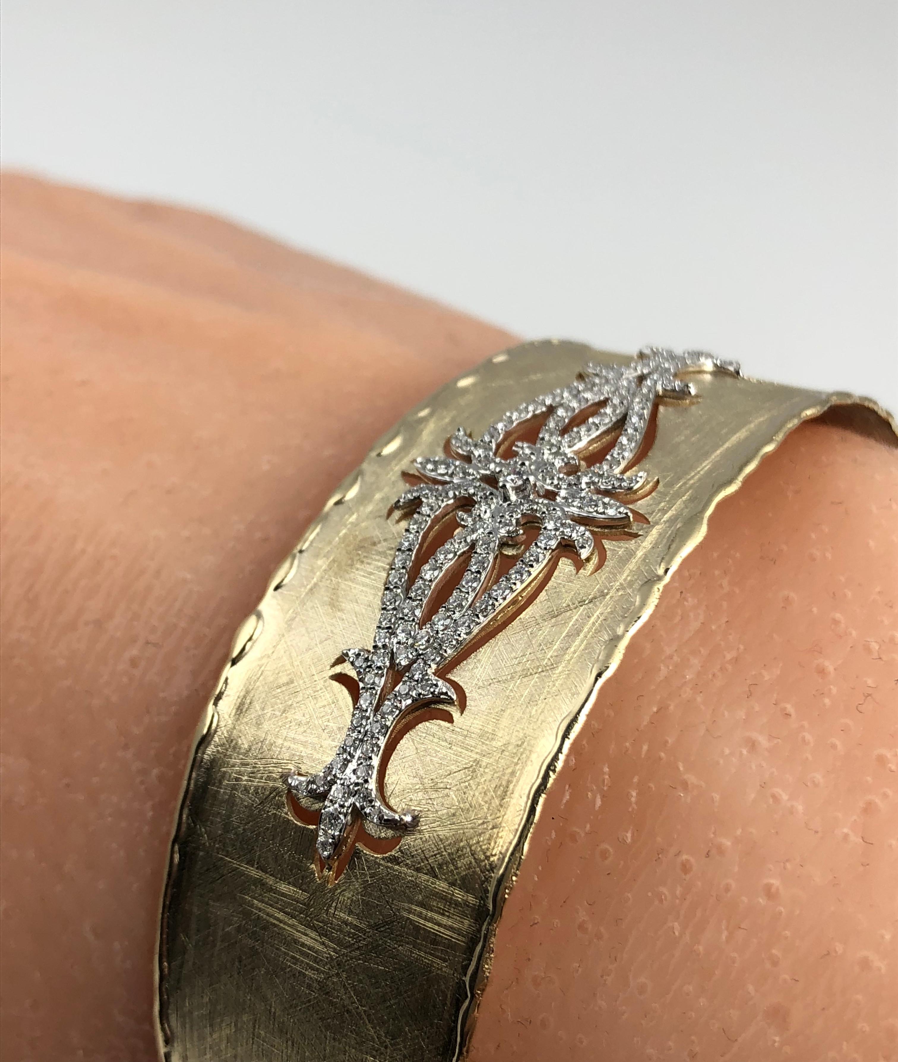 (DiamondTown) This rustic bangle has a brushed yellow gold design, accented by a diamond- accented cutout opposite the opening. The bangle is flexible enough to pass over the hand, without any hinge or buckle.

The bangle is set in 14k Yellow and