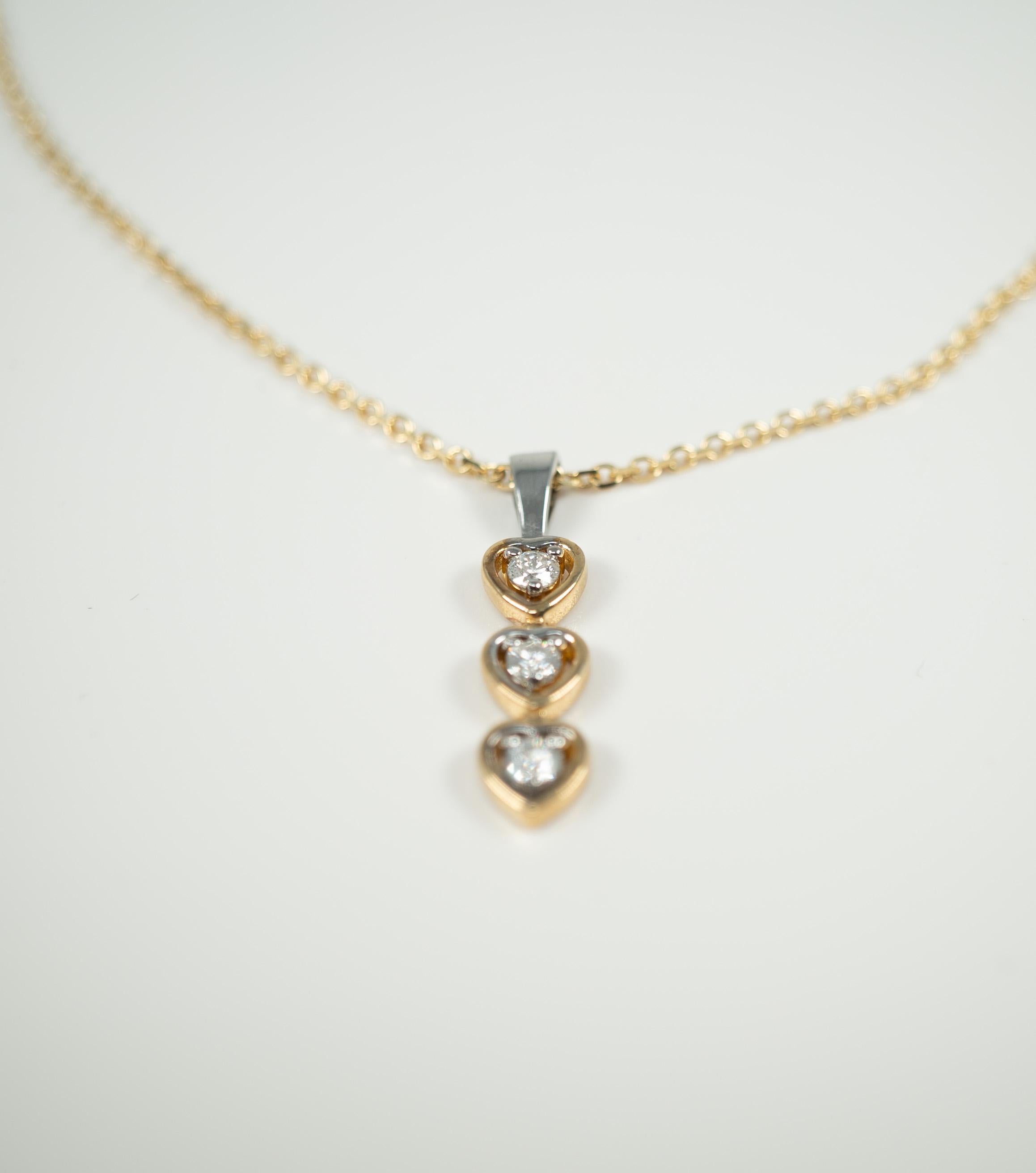 For that special person!  Or for yourself!  This 14 karat yellow gold chain suspends a yellow and white gold, dangle style pendant with yellow gold heart forms encircling three round diamonds.

Length of pendant:  1 inch