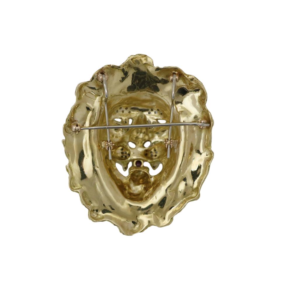 18k Yellow and White Gold Lion Head Pendant Brooch. The diamonds weigh approximately 0.50 carats, 1 ruby weighing approximately 0.30 carats and 2 emeralds weighing approximately 0.25 carats total weight.  The pendant measures 2.5 inches in length by