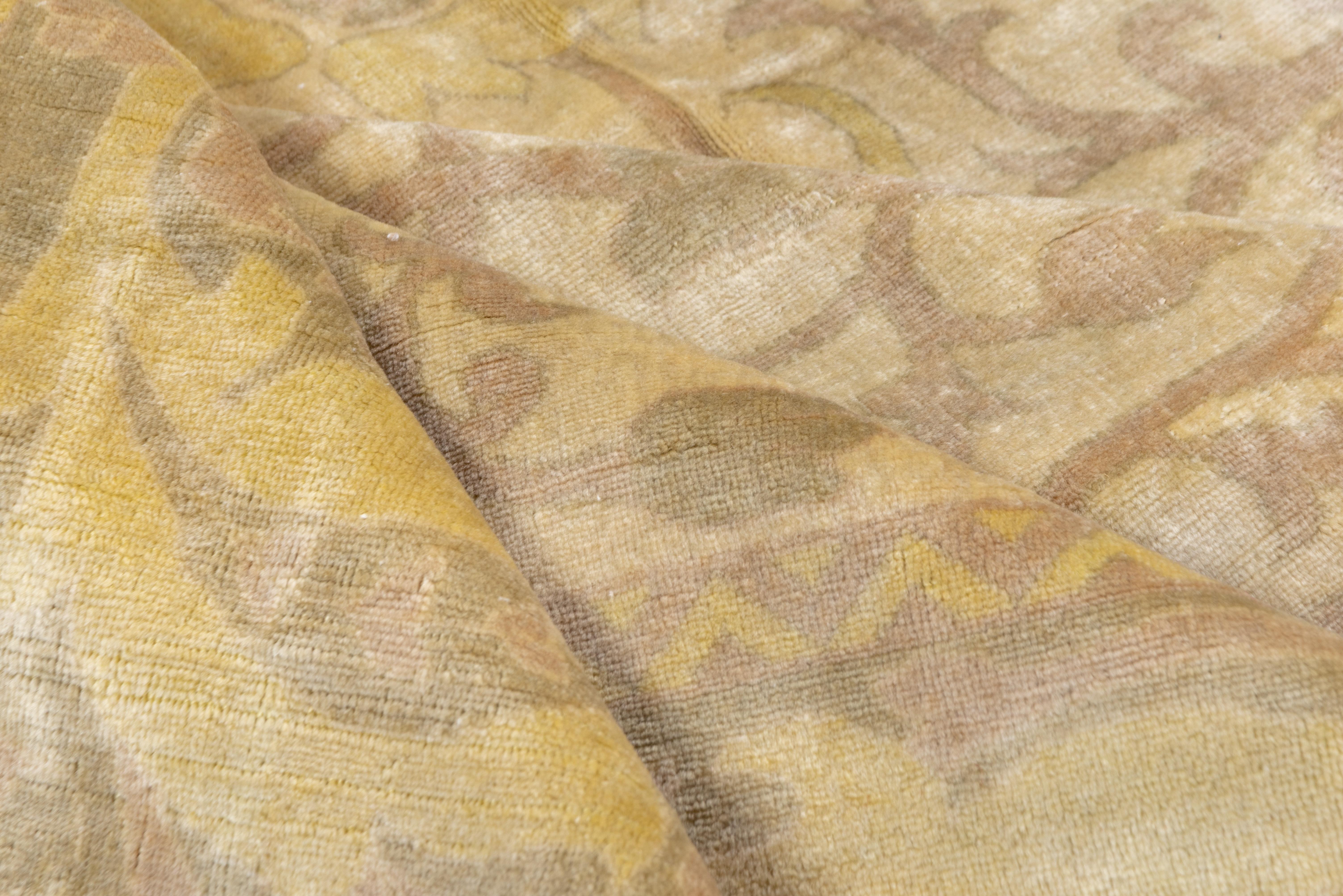 This is a softly, toned eastern Turkish town rug in an unusual format, with a creamy old ivory field accented in yellow and green, with an all-over flower, stem and leaf pattern. A straw leaf meander patterns the border.