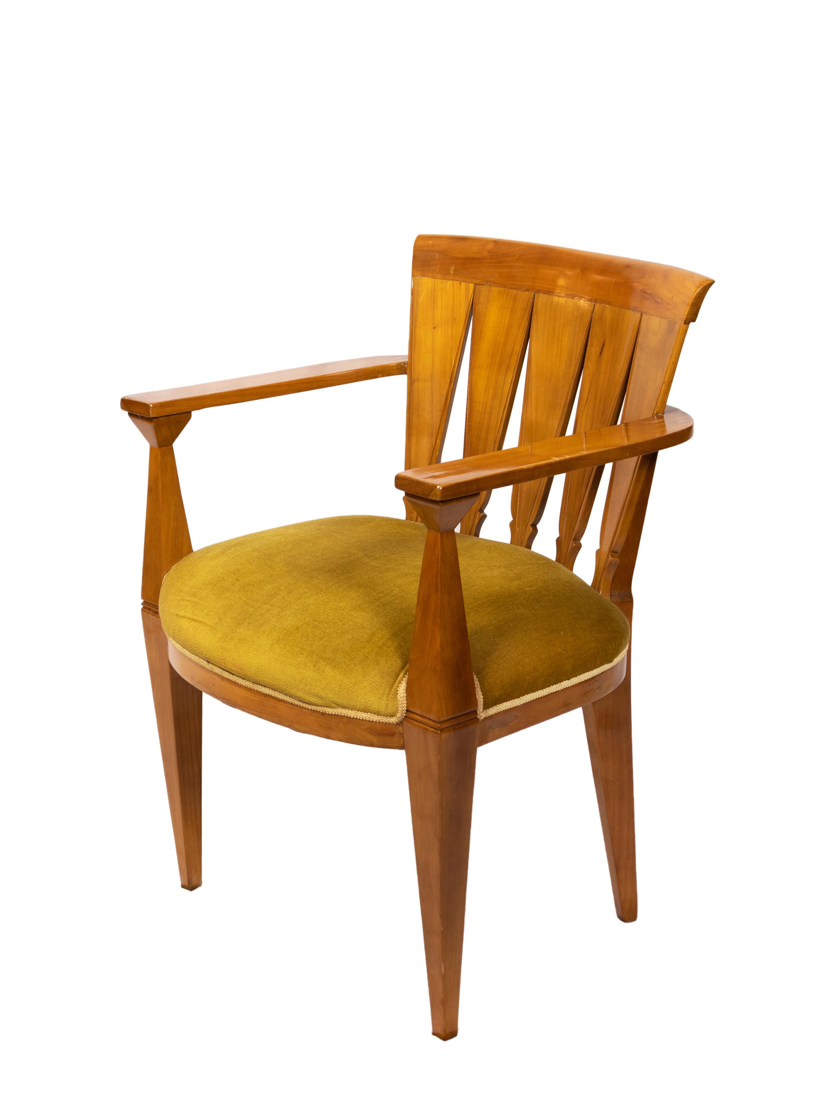 An Art Deco armchair with scalloped wooden backrest, armrests and wide seat, mustard-coloured upholstery.