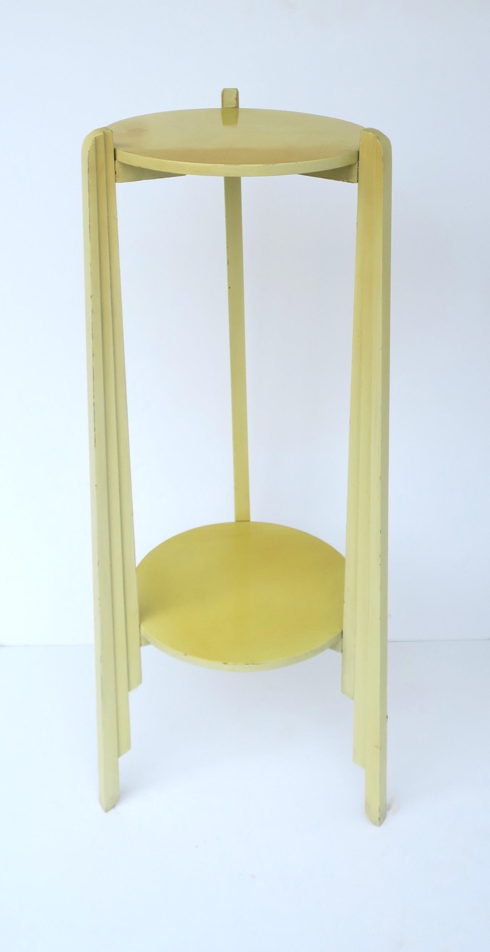 **There are two available, each sold separately, as per listing.

A yellow column pillar pedestal stand with lower shelf, Art Deco period, circa early to mid-20th century. Column is wood with a yellow paint finish, tri-pod legs with Art Deco detail,