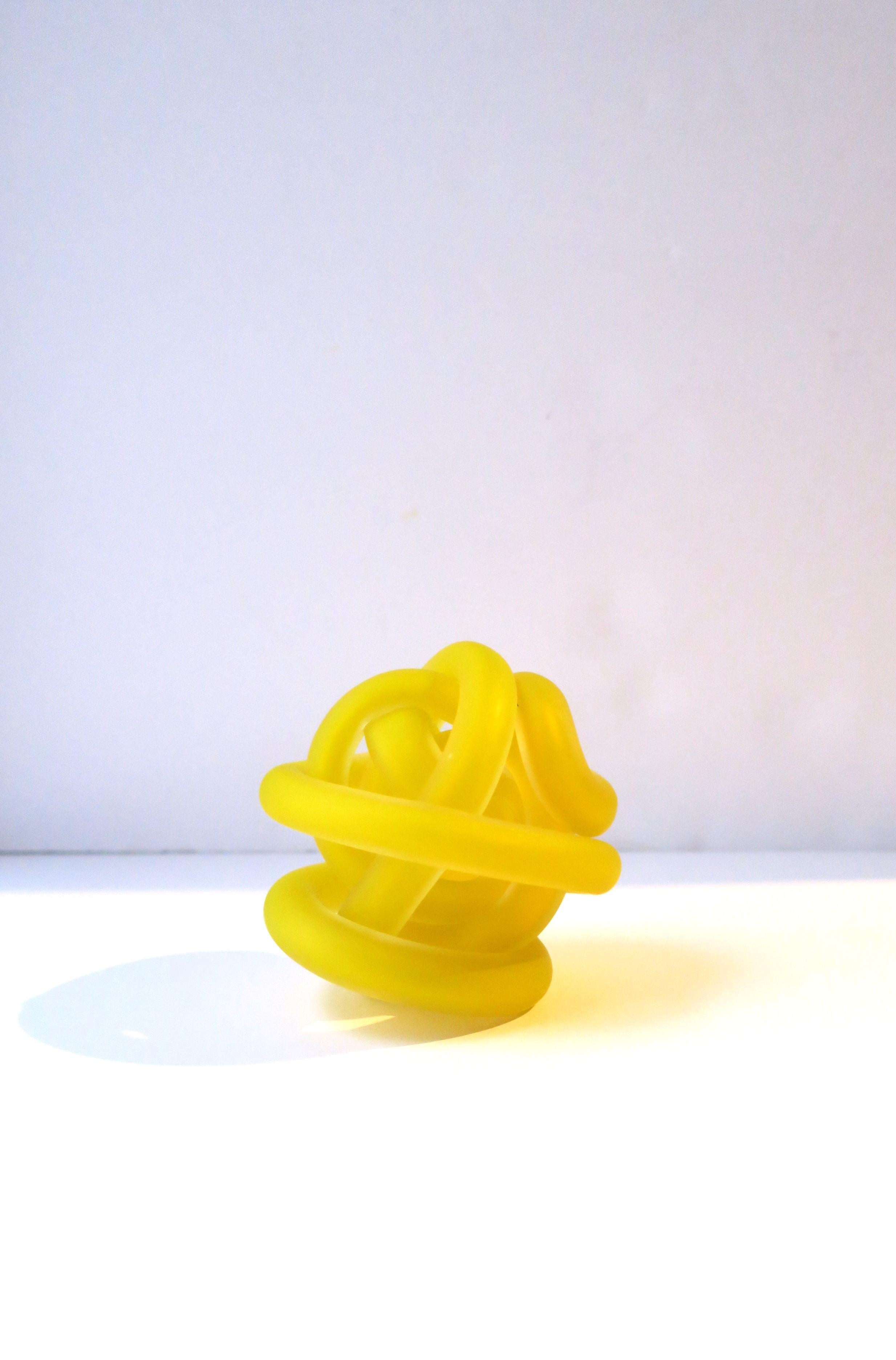 A yellow art glass knot sculpture decorative object, circa early 21st century. A beautiful pop of color with this contemporary art glass sculpture decorative object piece. A great item for a desk, bookshelf, cocktail table, on top of books, etc.