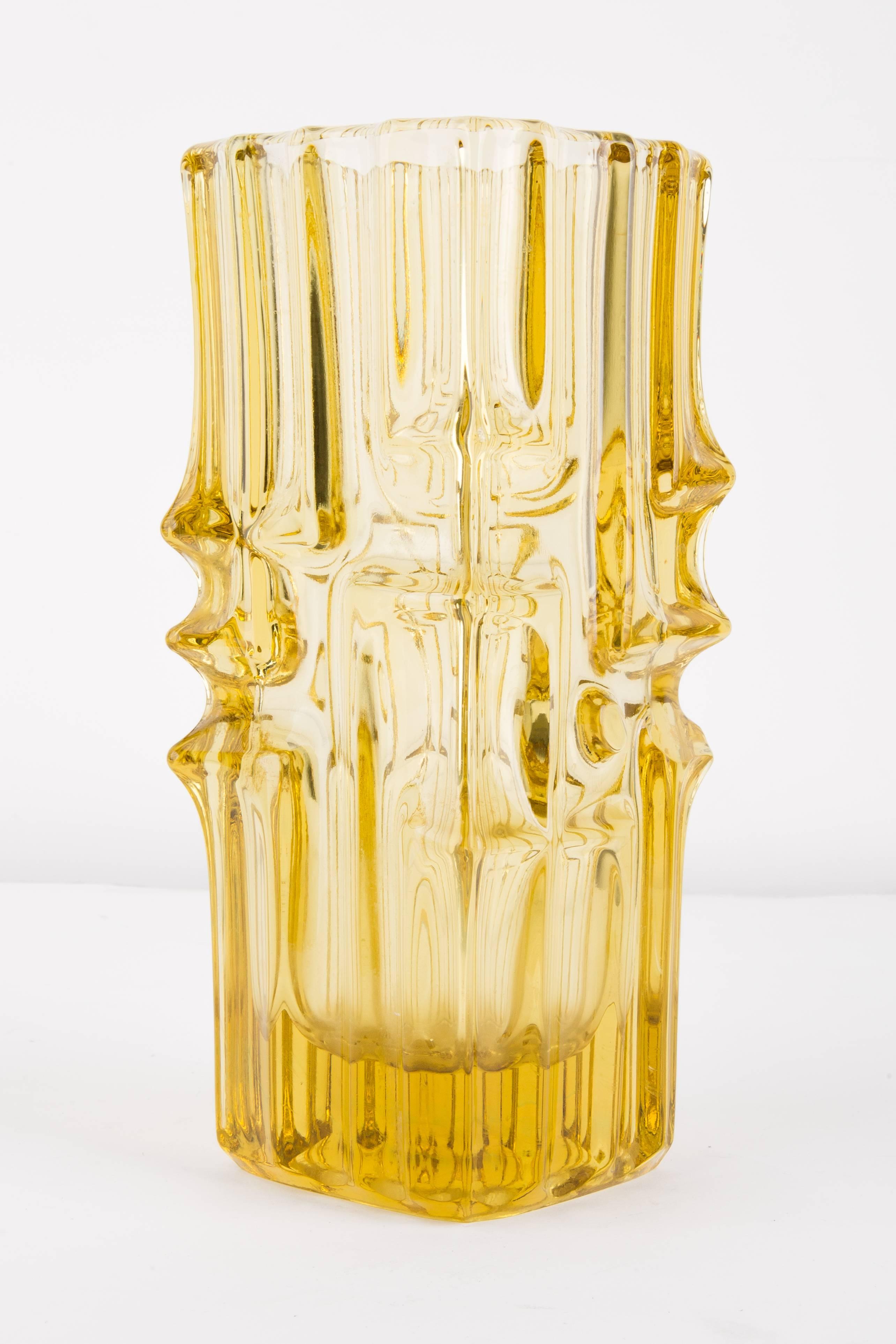 Vase formed by hand using traditional metallurgical technique. It was made of colored glass in a shade of lemon. The surface of the object with vertical grooves, which in the middle part change direction, merge and merge, giving a decorative effect.