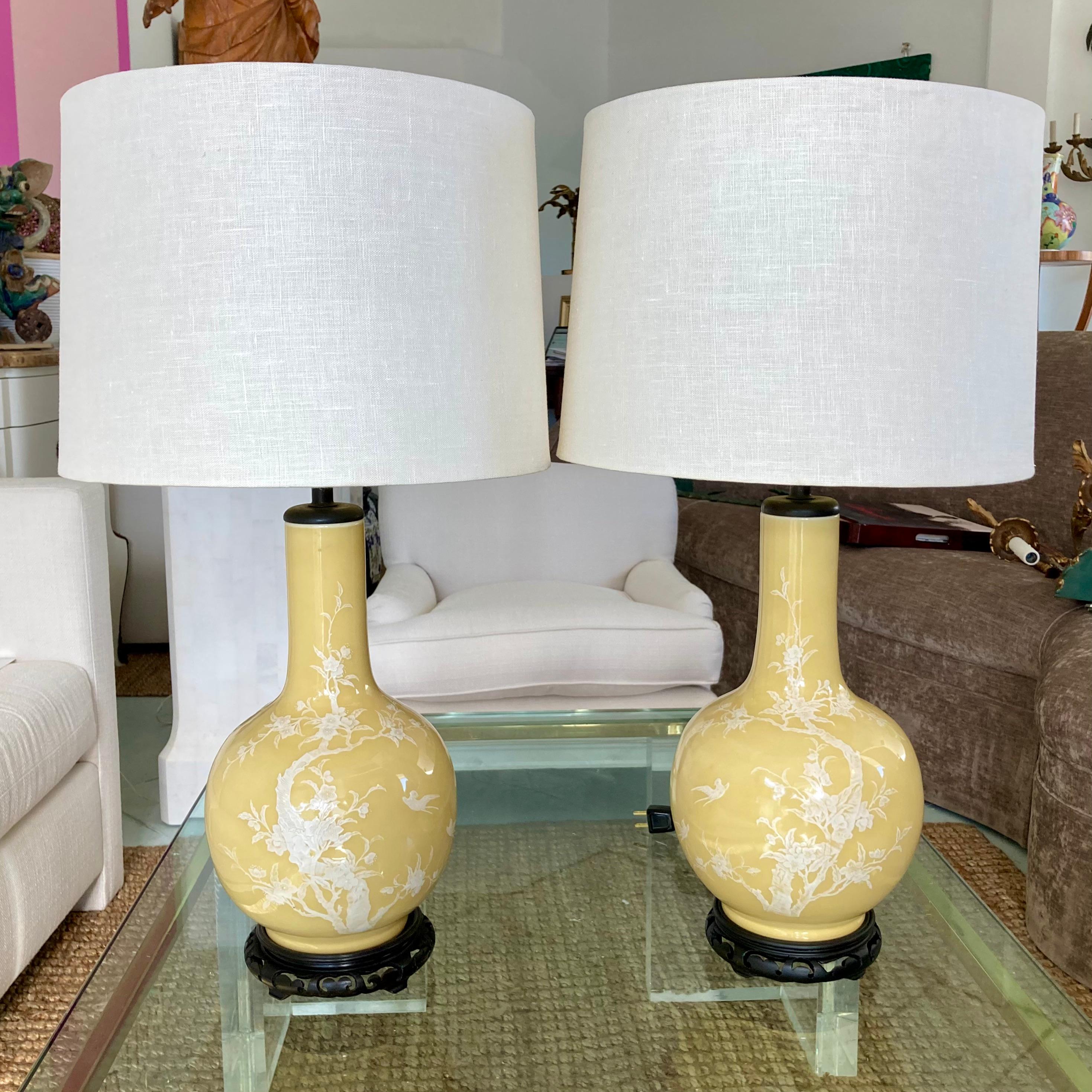 Beautiful pair of yellow Asian porcelain chinoiserie table lamps on carved wood bases. Add them to your chinoiserie inspired interiors and table tops.