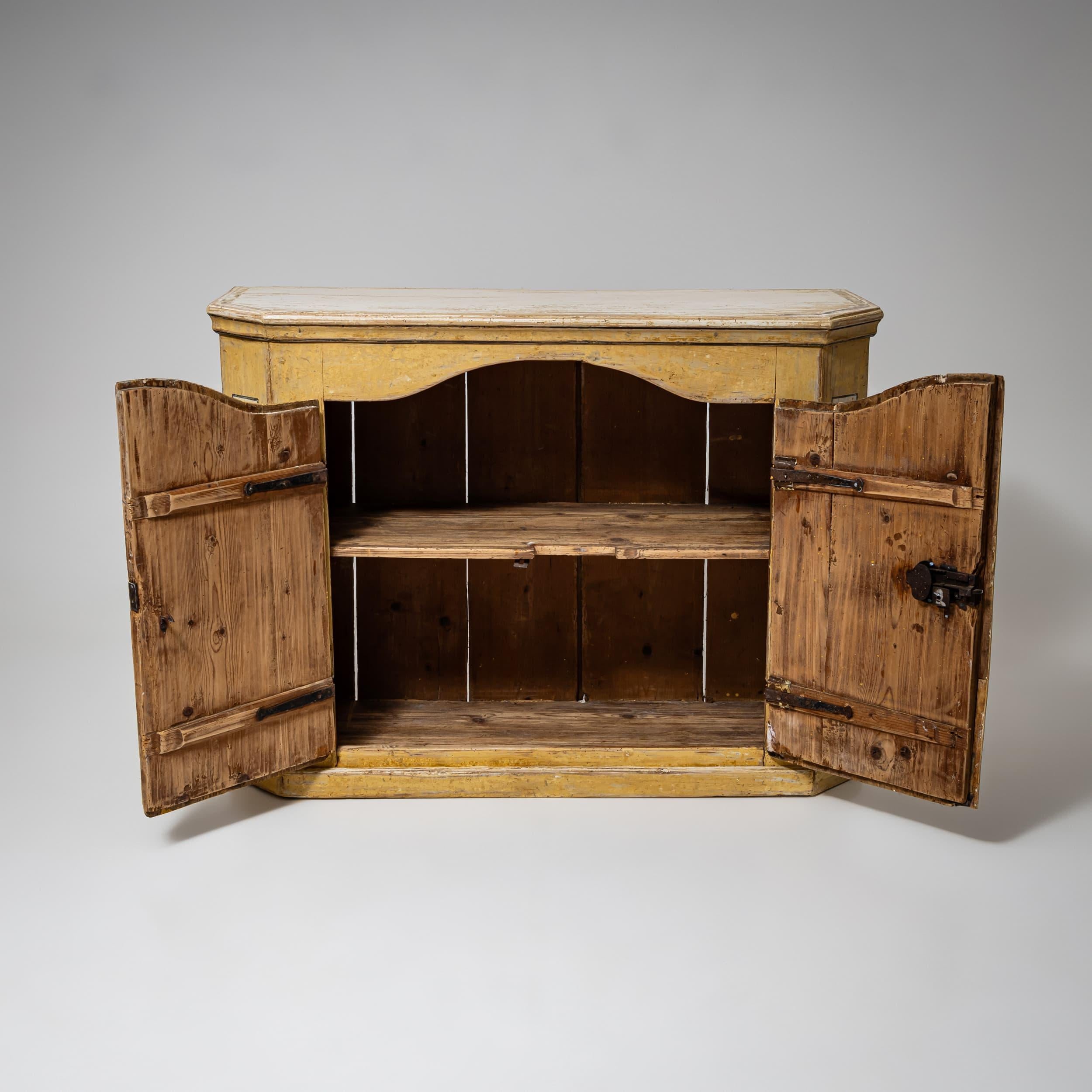 Charmant buffet baroque du XVIIIe siècle avec portes incurvées et panneaux latéraux biseautés. La finition jaune nouvellement appliquée avec une patine antique met en valeur le design élégant. Les motifs d'urnes et de fleurs de lys peints à la main