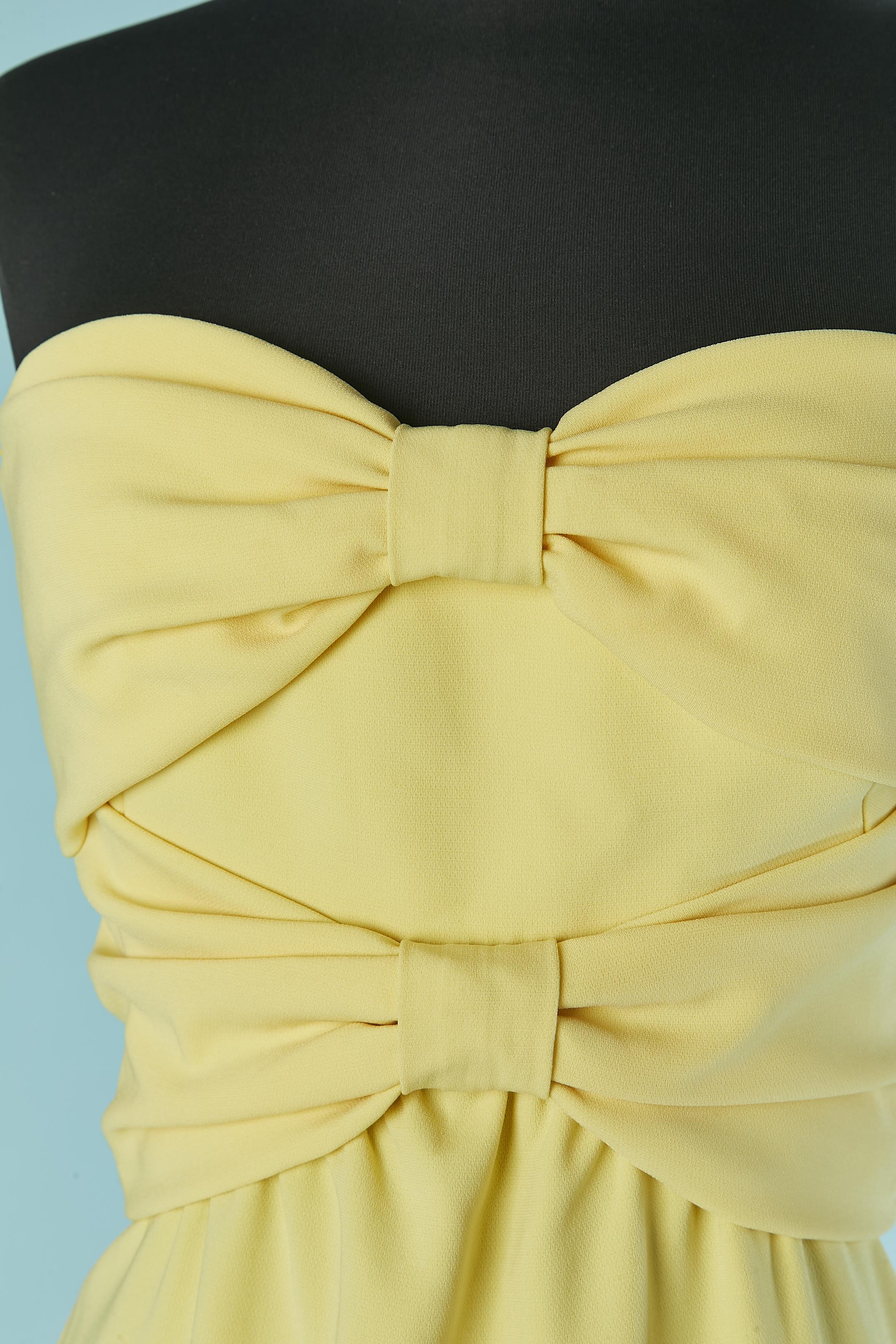 Yellow bustier evening dress with 2 bows on the bust. Main fabric composition: 70% triacétate, 30% polyester. 
Satin lining only inside the bust. Boned. Invisible zip on the left side. 
Total front lenght : 140cm
Total back lenght: 155cm 
SIZE 40