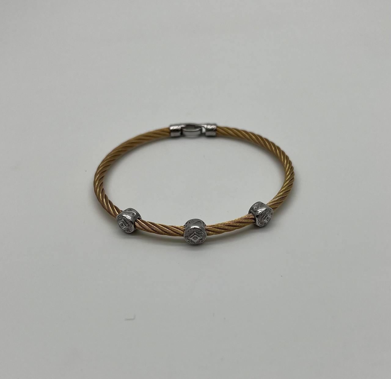 Dieses exquisite Armband zeichnet sich durch ein gedrehtes goldfarbenes Kabeldesign aus, das mit drei kreisförmigen Akzenten aus 18 Karat Weißgold mit Diamanten verziert ist. Jeder Akzent ist detailliert ausgearbeitet und verleiht ihm einen Hauch