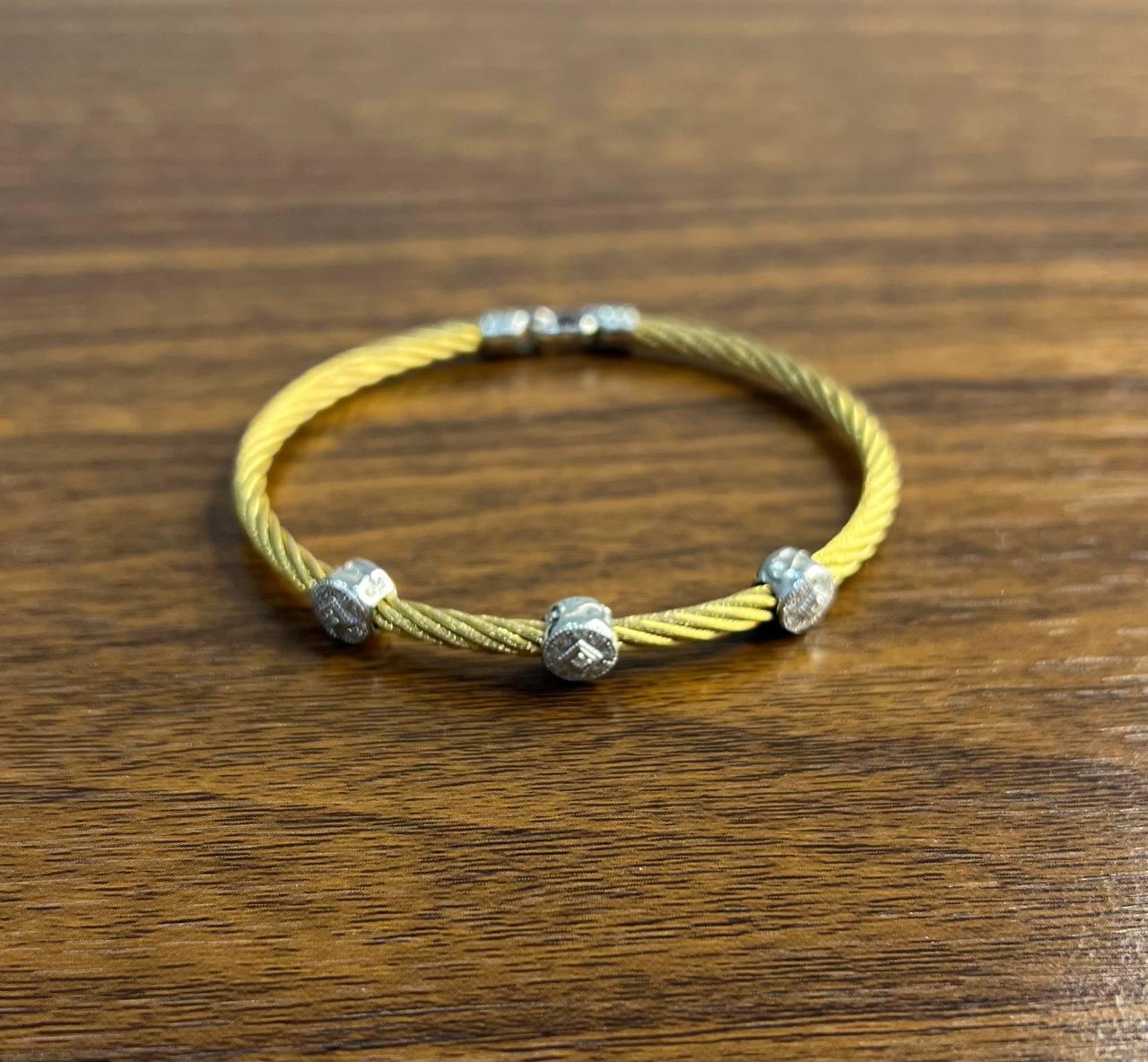 Esta moderna pulsera presenta un diseño de cable de acero trenzado en tono dorado. Está adornado con tres cuentas de oro blanco espaciadas uniformemente con diamantes de 0,20 ctw, cada una de ellas con intrincados detalles. El estilo elegante y