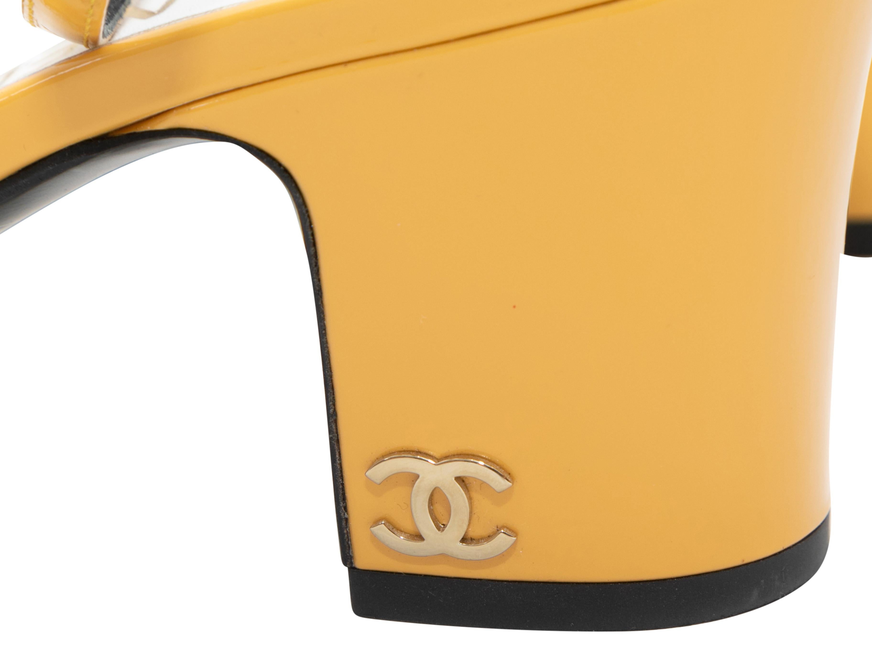 Yellow patent leather ankle strap heeled sandals by Chanel. Silver-tone buckle closures at ankle straps. 2.5