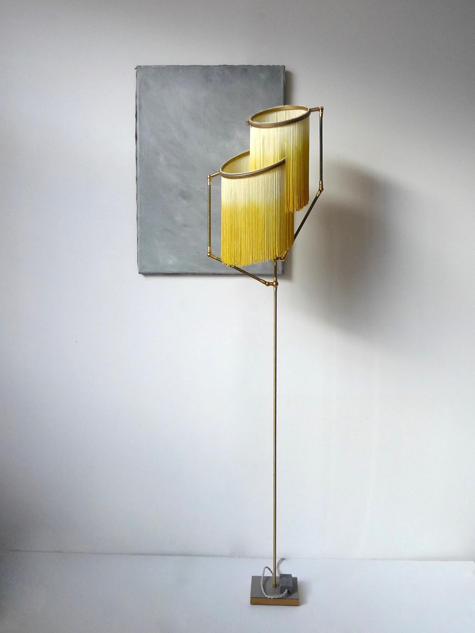 Yellow Charme floor lamp, Sander Bottinga

Dimensions: H 153 x W 38 x D 25 cm
Handmade in brass, leather, wood and dip dyed colored Fringes in viscose.
The movable arms makes it possible to move the circles with fringes in different