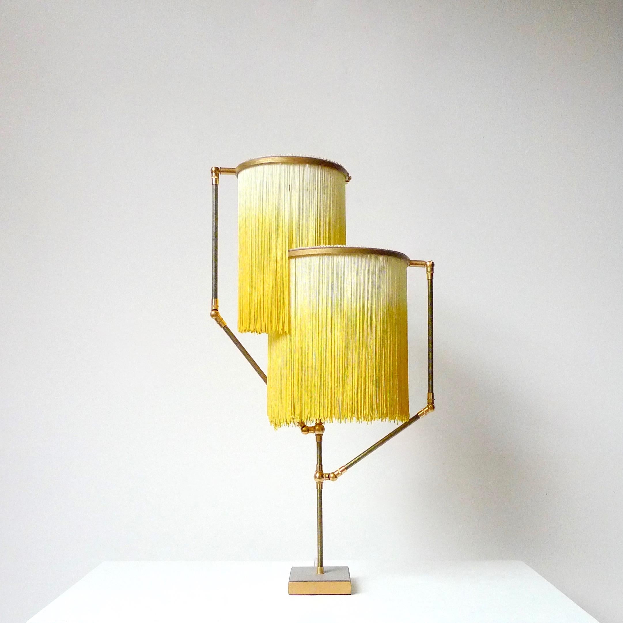 Yellow Charme table lamp, Sander Bottinga.

Dimensions: H 73 x W 38 x D 25 cm.
Hand-sculpted in brass, leather, wood and dip dyed colored Fringes in viscose.
The movable arms makes it possible to move the circles with fringes in differed