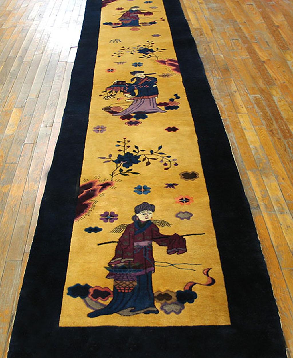 This yellow ground long runner features figures in traditional Chinese dress among rocky outcrops, clouds and airborne rosettes. Pictorial runners are rare and this northeast Chinese rug must have been a special order. The figures were probably
