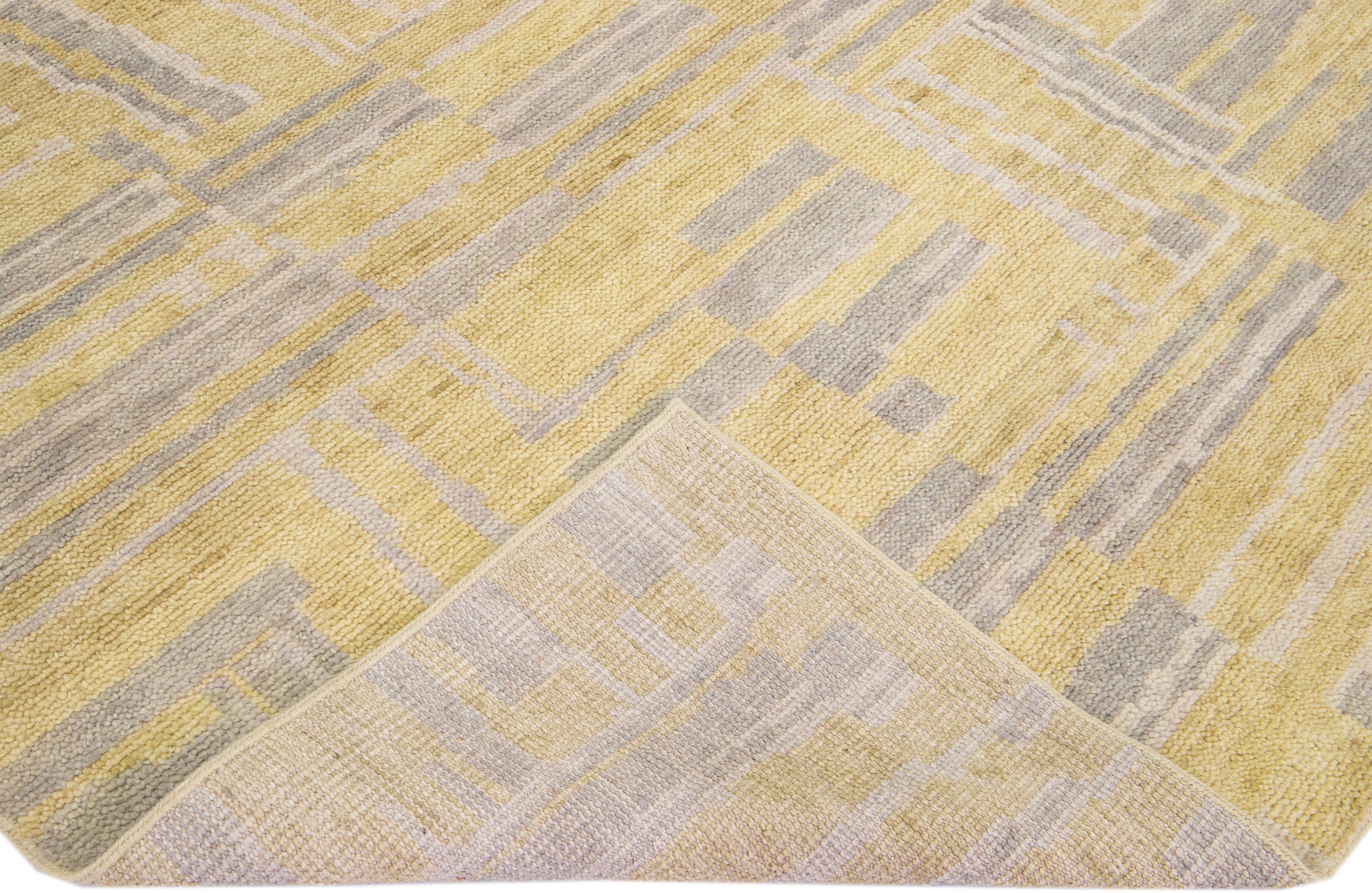 Schöne zeitgenössische Teppiche von Thom Filicia Home Collection. Dieser indische handgeknüpfte Teppich ist aus Wolle gefertigt und hat ein goldenes Farbfeld und hellgraue Akzente im gesamten Design. 
Thom Filicias Auge für exquisite Details und