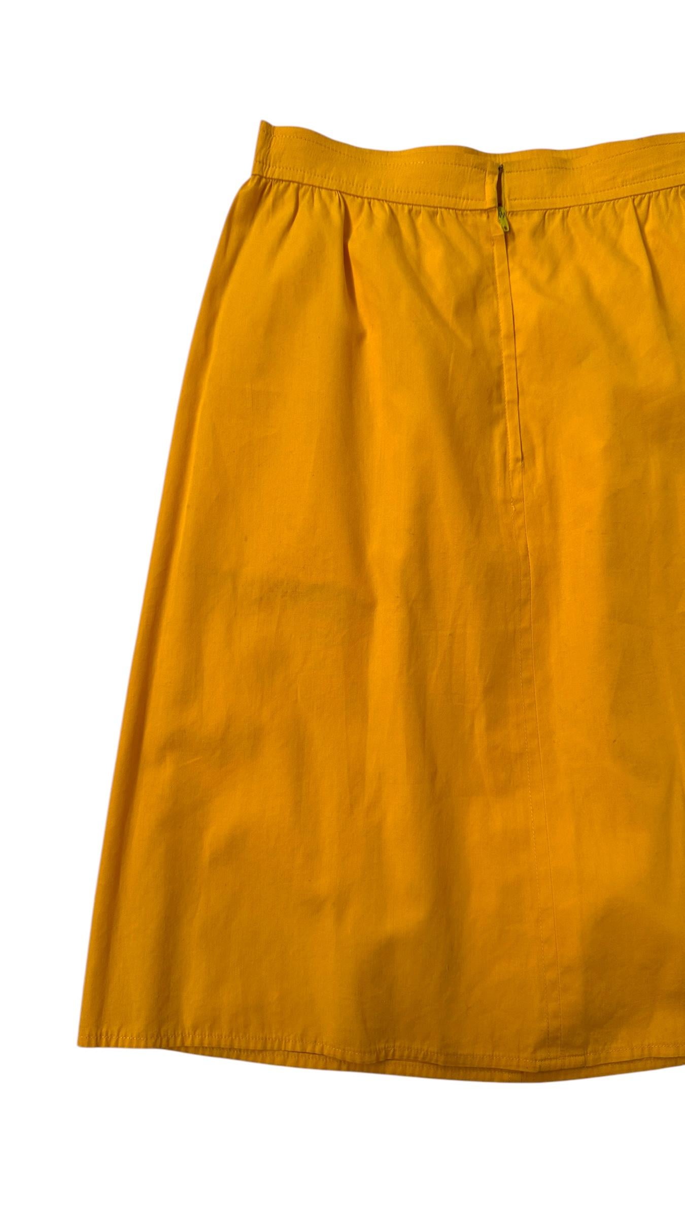 Charming vintage two-piece ensemble composed of a floral cropped blouse and matching high-waisted skirt in vibrant mustard yellow cotton. The top features a delicate black background with multicolored floral print, contrasted by bold yellow trims,