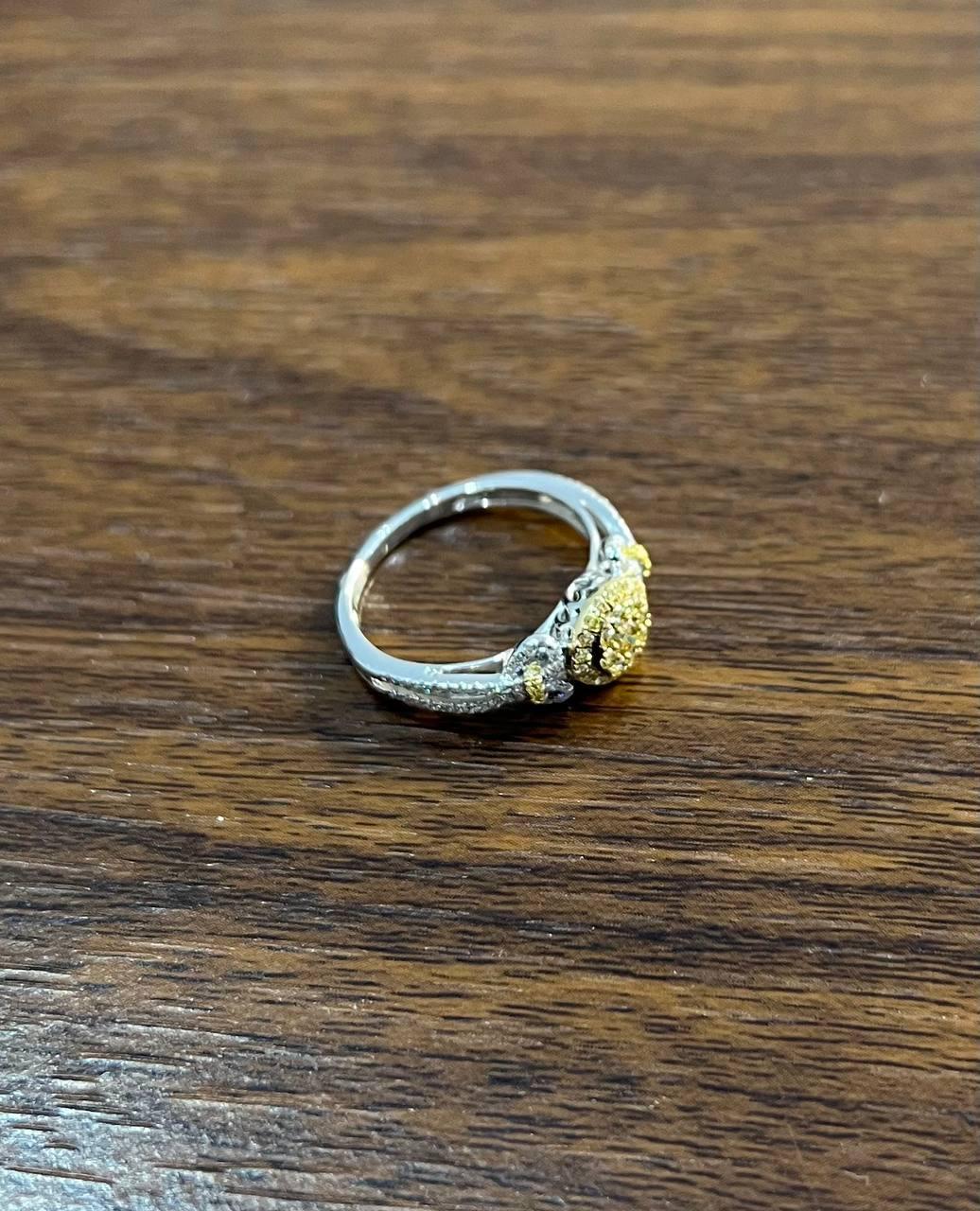 A fusion of elegance and brilliance.
This stunning ring features a captivating central cluster of yellow diamonds, encircled by a halo of smaller white diamonds. The intricate design is set on a sleek band, enhancing the overall sparkle and
