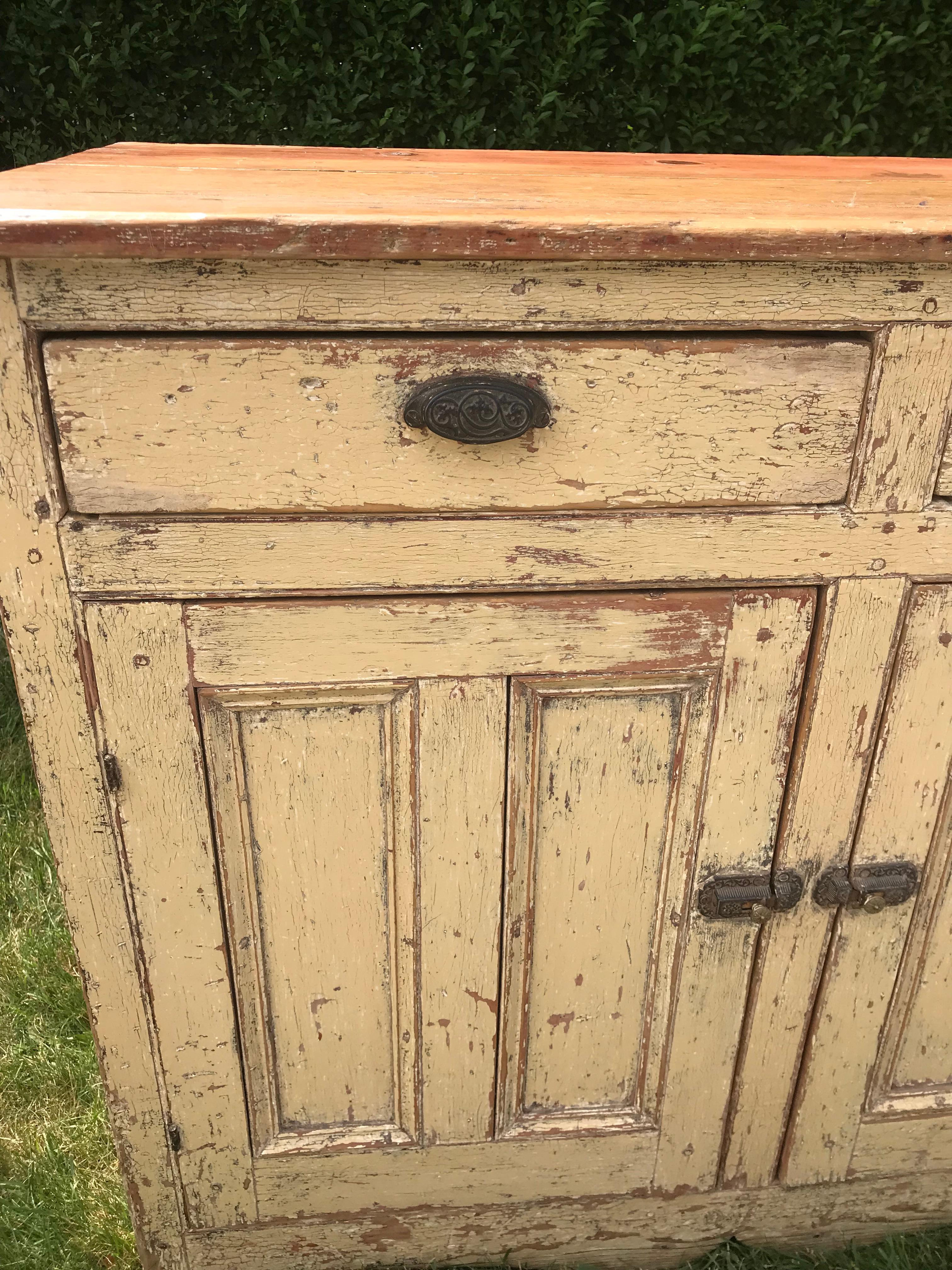 19th century dresser base in old yellow paint with unpainted, natural top.  Two drawers over two paneled doors.  Interior with single shelf.  Shaped skirt.  New Brunswick, circa 1860.