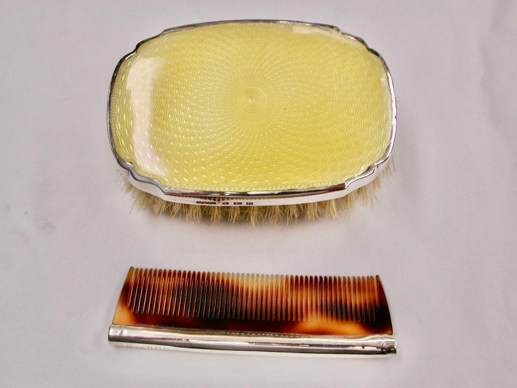 Yellow Enamel and Silver Childs Hairbrush with Comb, Dated 1927, Birmingham
The brush is fitted with pure bristle.
The comb is hallmarked for the same year.
The leather covered box is missing the front clip.
Maker is Daniel Manufacturing Company.