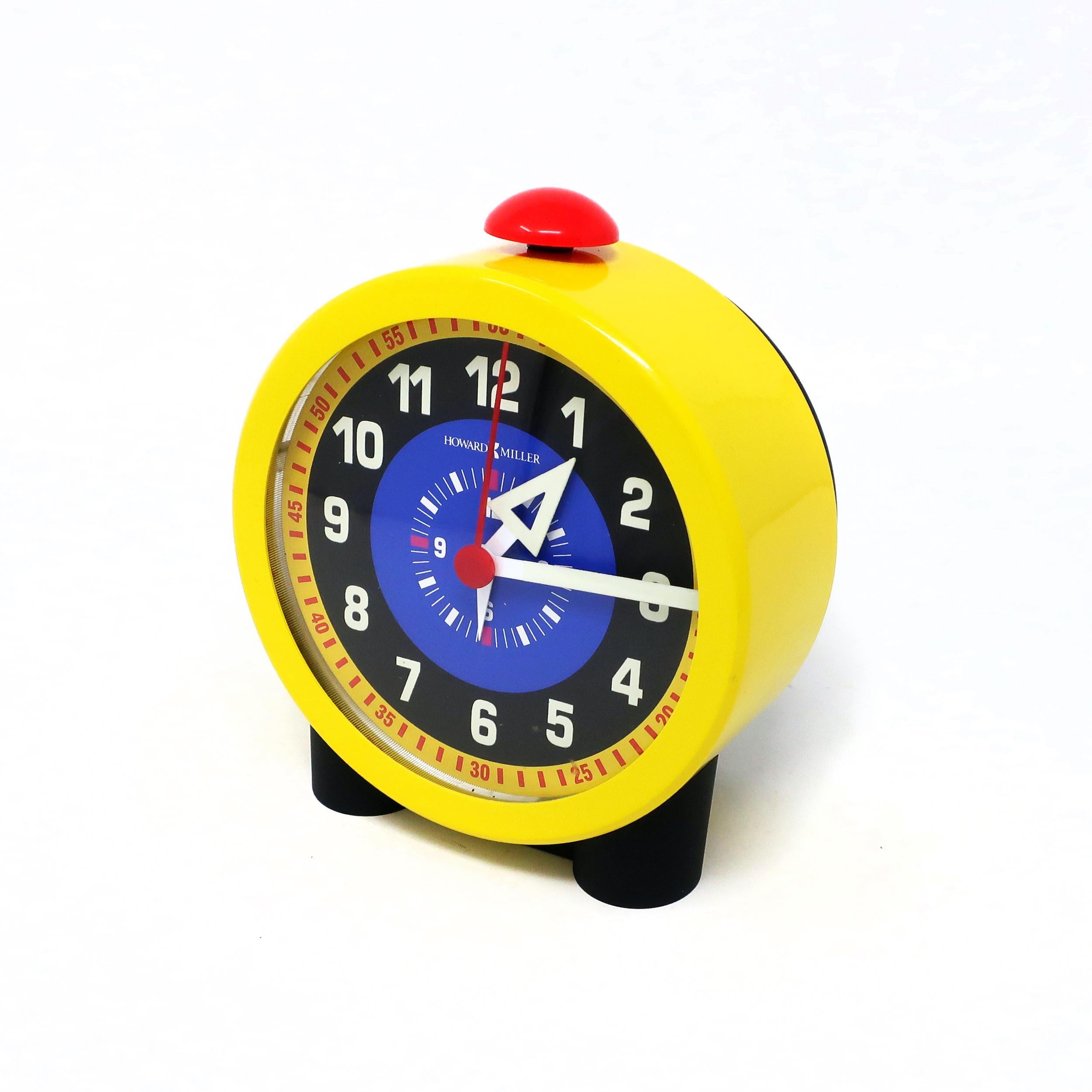 In the style of George Nelson's pioneering clock design for Howard Miller, this alarm clock has a multi-colored face, bright yellow metal case, and prominent red alarm button on its top. Makes a delightfully classic metal alarm clock sound when it