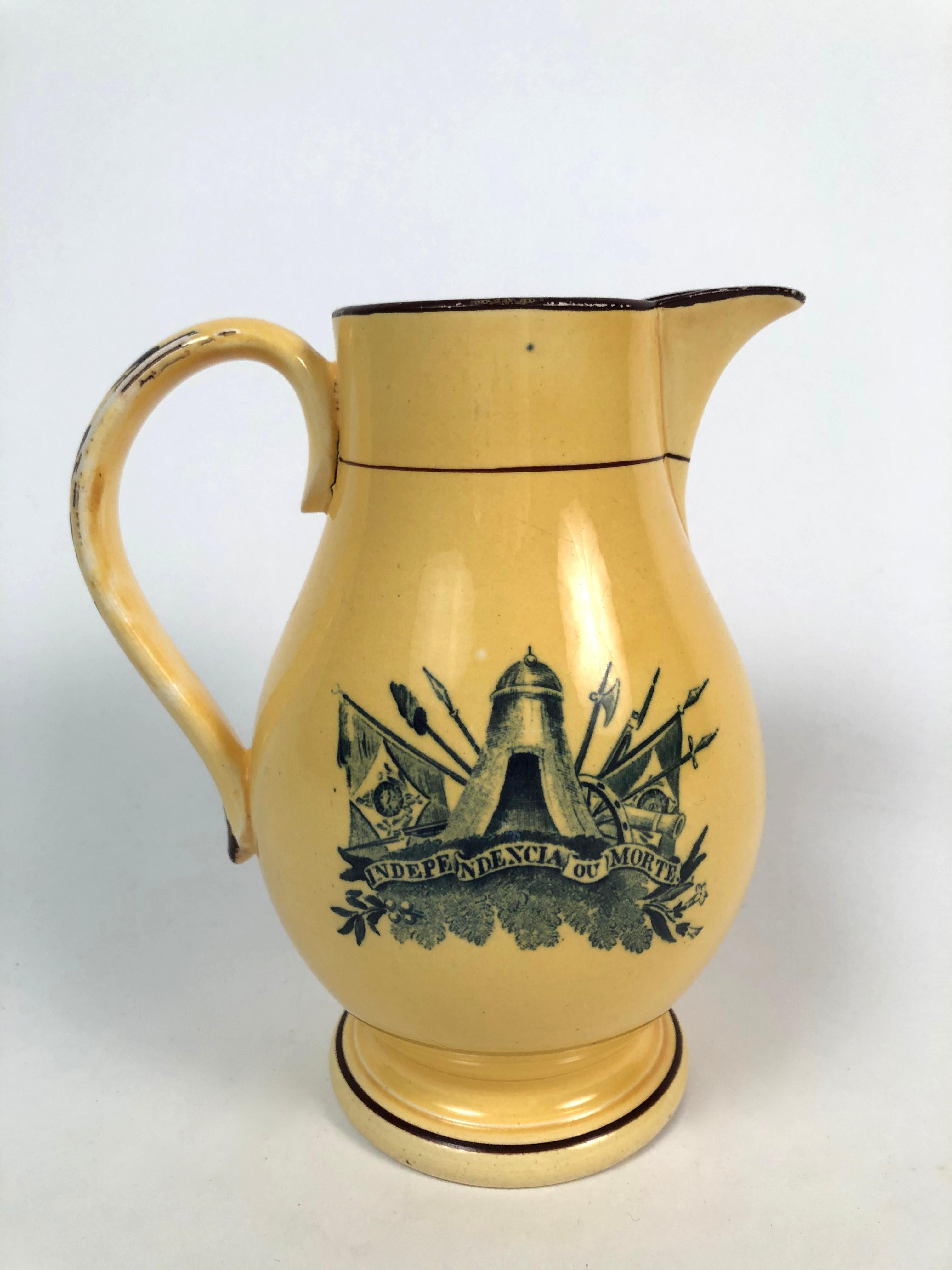 A rare Staffordshire pottery pear shaped pitcher with strap handle, made to commemorate the independence of Brazil from Portugal in 1822, transfer printed in blue on canary yellow with the slogan 