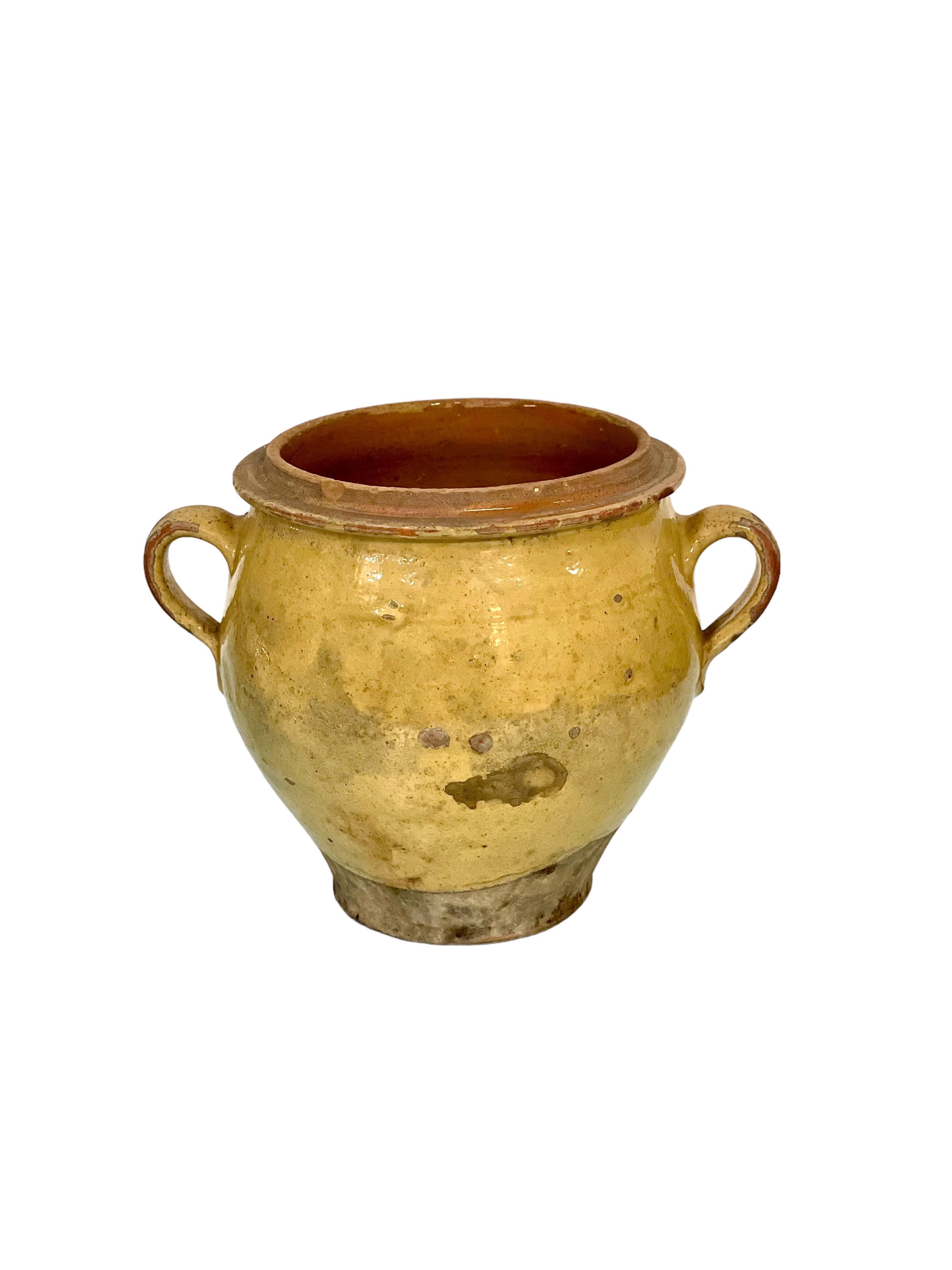 Traditional French terracotta confit pot with yellow glaze and two side handles. Dating from the 19th century, this vessel was used to conserve food – mainly meats in fat – before the invention of refrigeration.