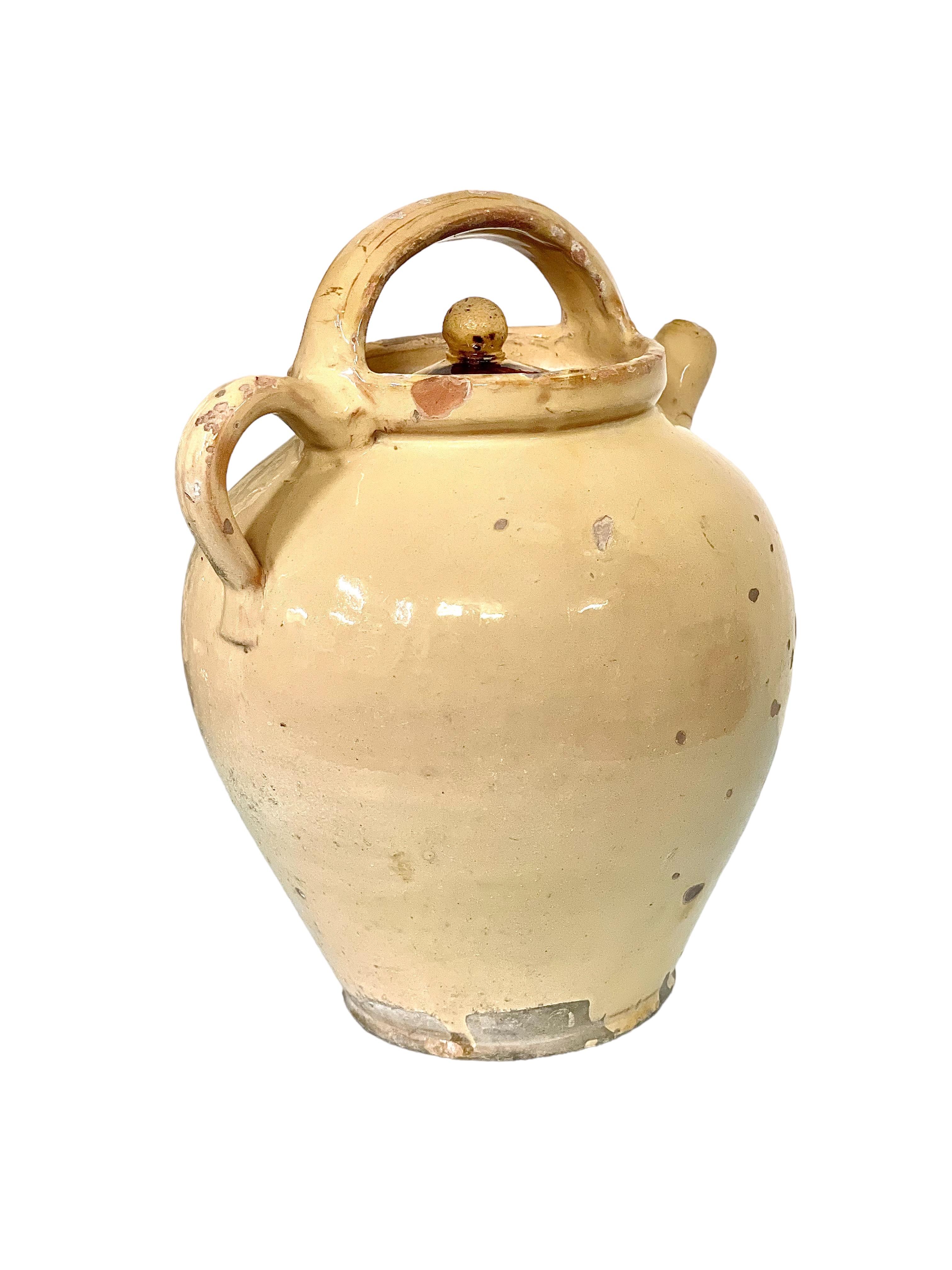 A charming and authentic ceramic water pitcher, or 'cruche', with top handle and lid, made of ochre-glazed terracotta earthenware. Originally a piece of utilitarian kitchenware, used for transporting and storing cold water, this wonderfully