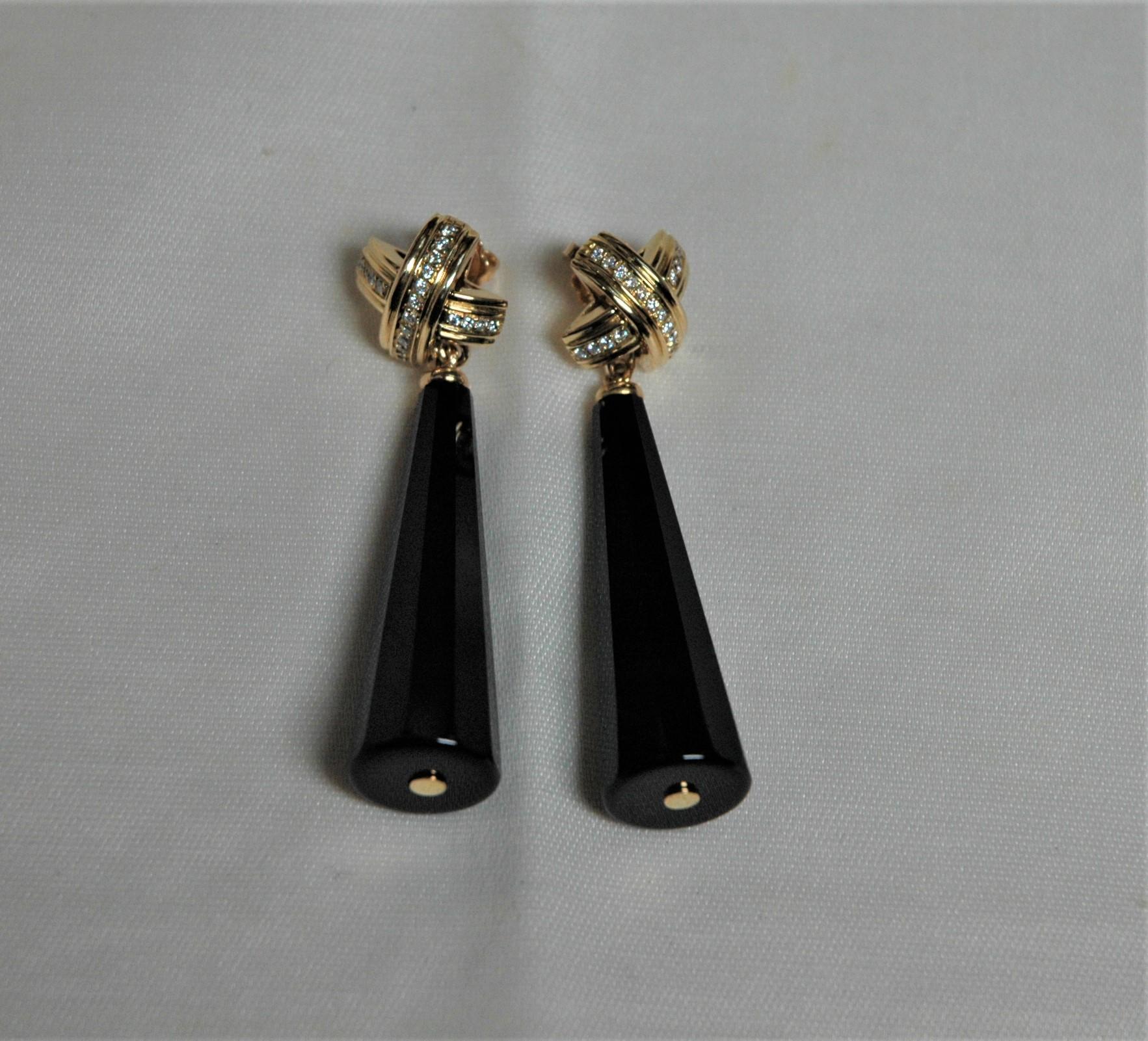 Very original dangle earrings. They have been made by Italian manufacturing with a top like a cross in yellow gold 18 kt and diamonds, brilliant cut, 0.48 ct. They are very particular about the shape of the onyx pendants, which are all faceted along