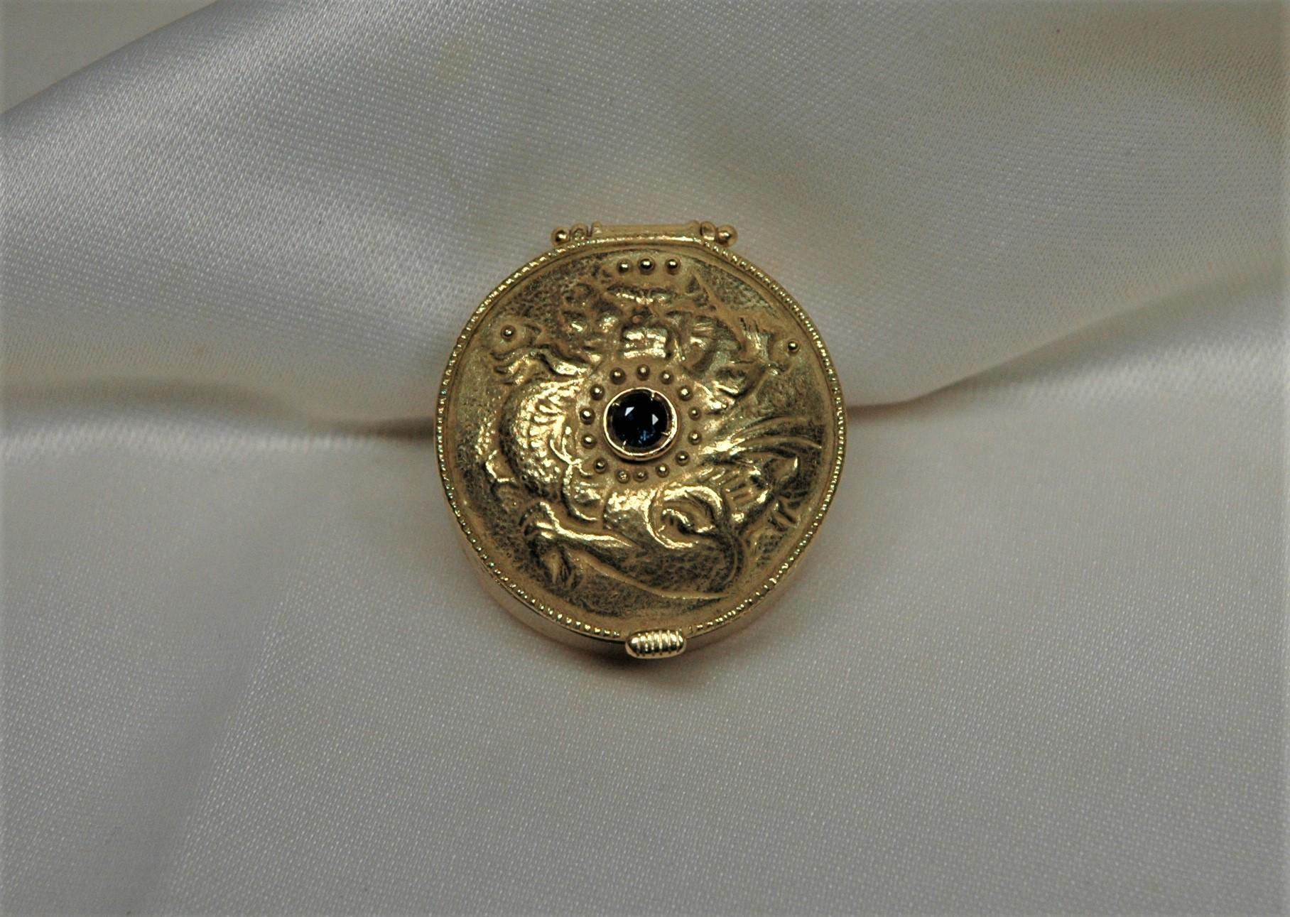 Hand-crafted gold box with blue sapphire embedded in the center.