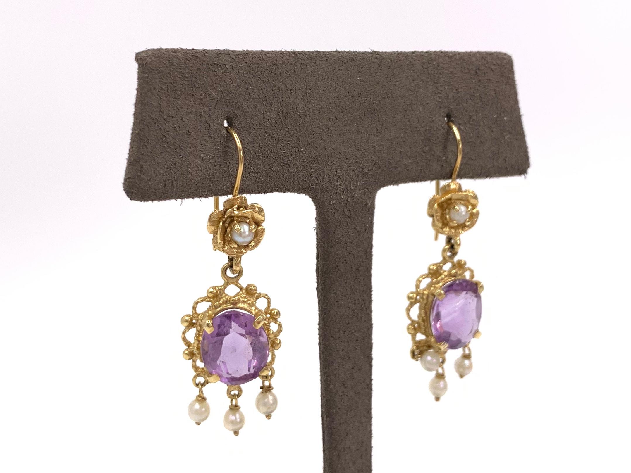14 Karat yellow gold Victorian inspired delicate and feminine drop earrings featuring oval light purple amethyst gemstones (measuring 10mm x 8mm) and 3mm ivory seed pearls. Earrings are fixed with kidney ear wire posts.