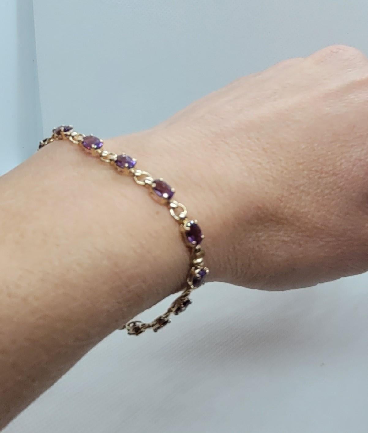 This is a beautiful yellow-gold amethyst bracelet, measuring 7.25 inches in length. The bracelet features 14 oval amethyst stones, each measuring 6 x 4 mm, secured with four prongs. The bracelet is made of 10kt gold and weighs 5 grams. It is 4mm