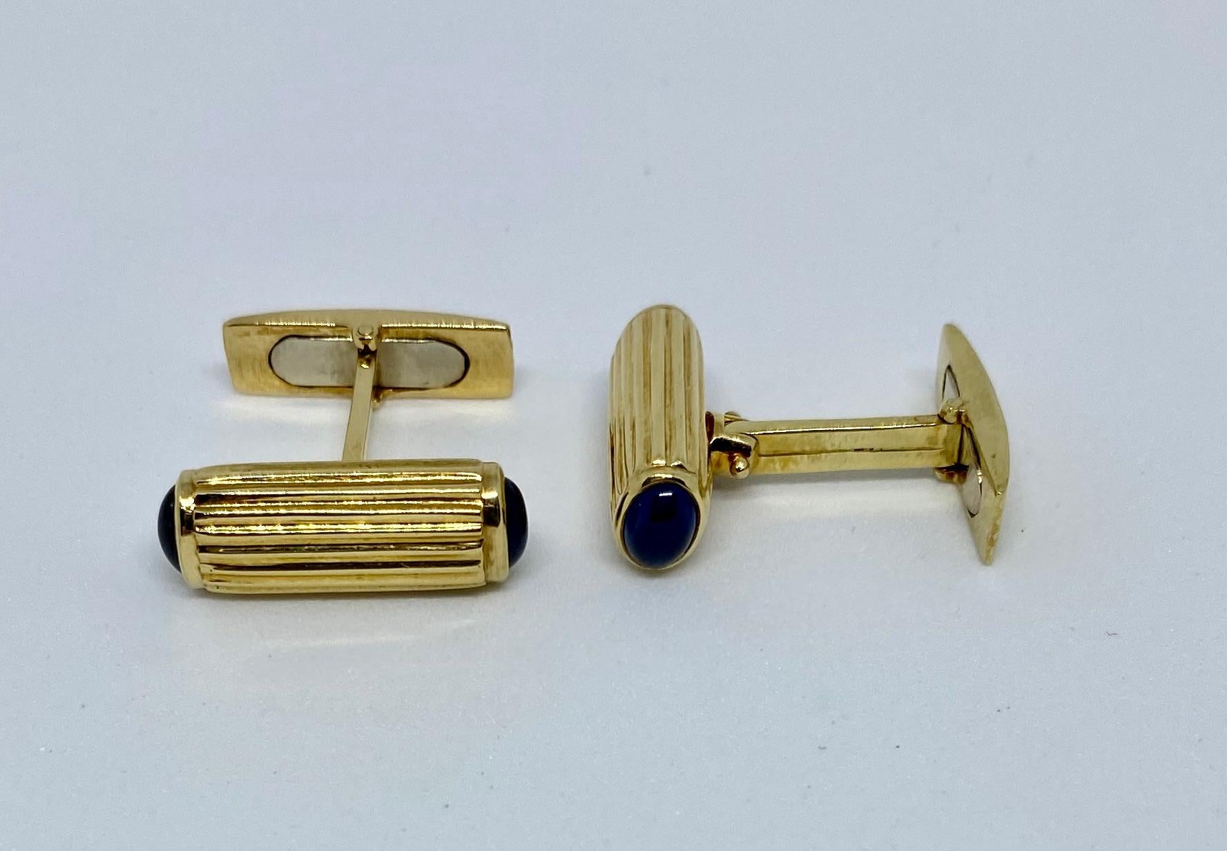 Very stylish, classic baton-style cufflinks featuring four cabochon-cut oval blue sapphires set in ribbed 18K gold.

The batons measure 20.6mm long and 7.6mm high. Each of the four oval sapphires measures 5.8mm by 4.3mm. The batons are connected to