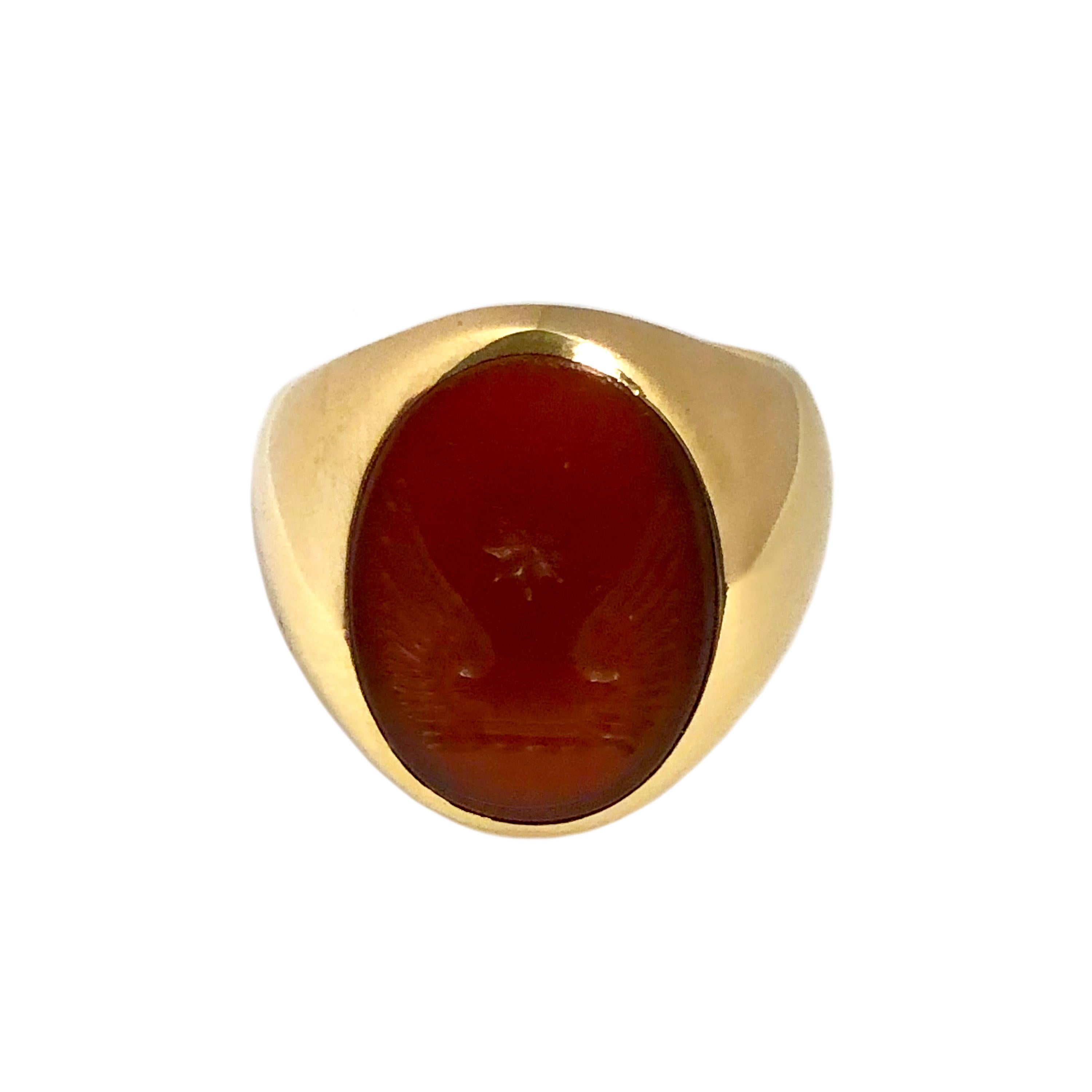 Circa 1910 14K yellow Gold Signet Ring, set with an oval Carnelian measuring 3/4 X 1/2 inch and is carved with a Double wings and Star Signet. The ring is solid with a good weight of 15.4 Grams. Finger size 7 1/4
