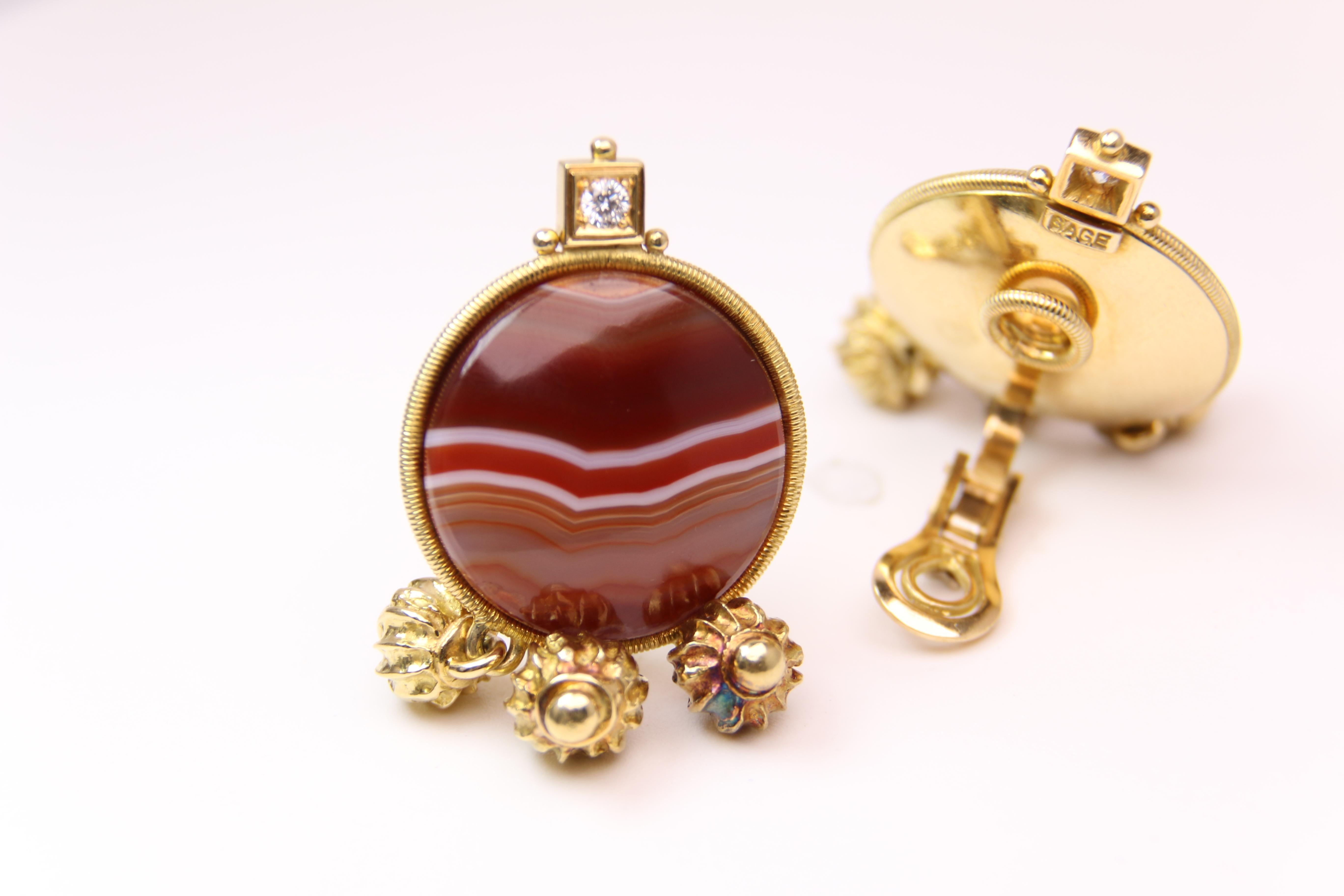 These stunning 18k Yellow gold and Carnelian Diamond Clip on Earrings from Elizabeth Gage weigh in at 43.9g. Earrings are marked Gage 750
Each earring features 1 round Diamond
The earrings measure 1.75 inches in length and 1 inch in width.
