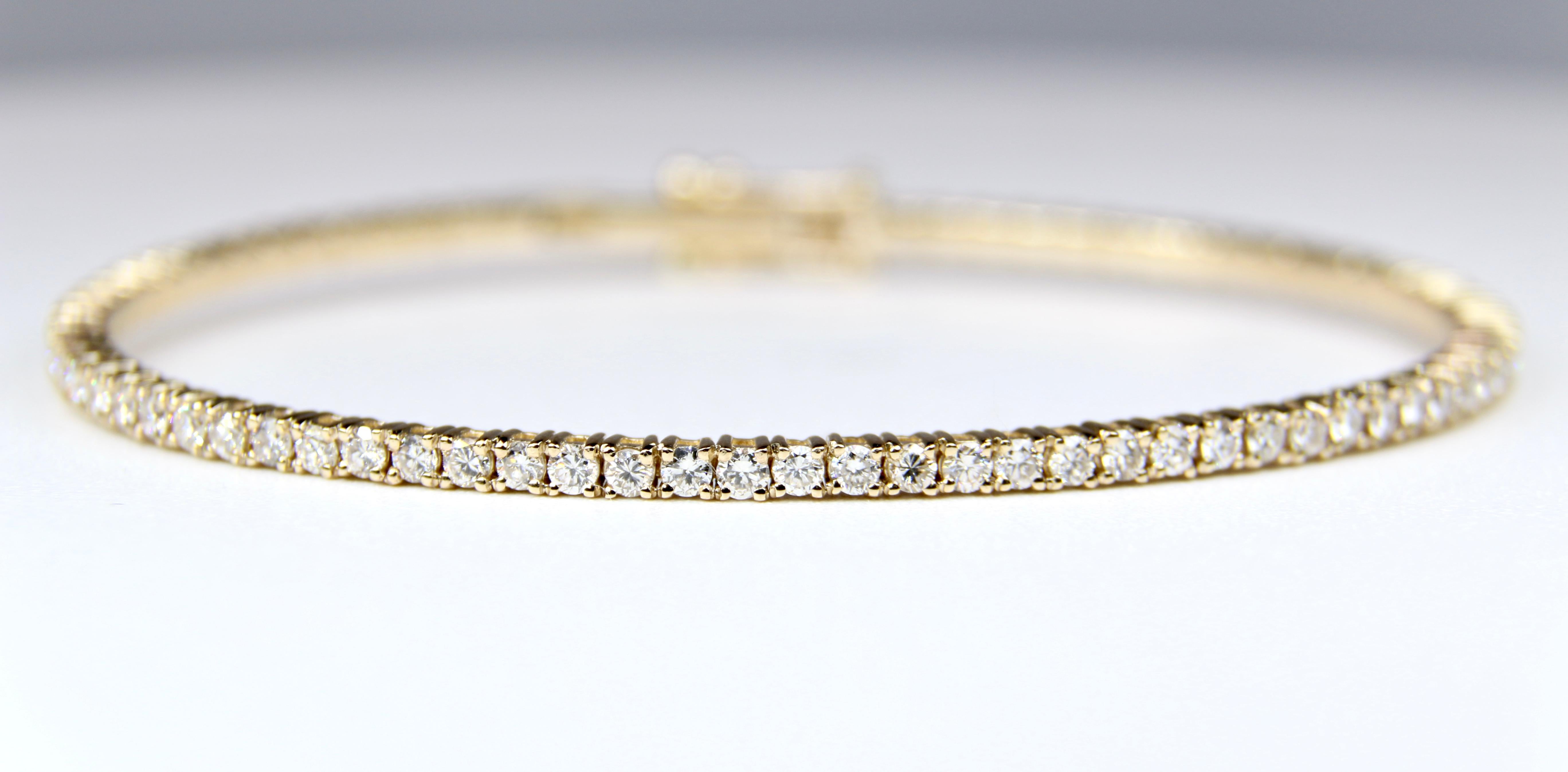 14K yellow gold and 74 round diamond flexible bangle bracelet. 
2 carats total weight, G-H color, VS2-SI1 clarity. The diamonds are set in 4 prongs.
The bracelet weighs 9.2 grams. Snap in clasp with Two figure 8 safety clasps.
7 inch bracelet, a