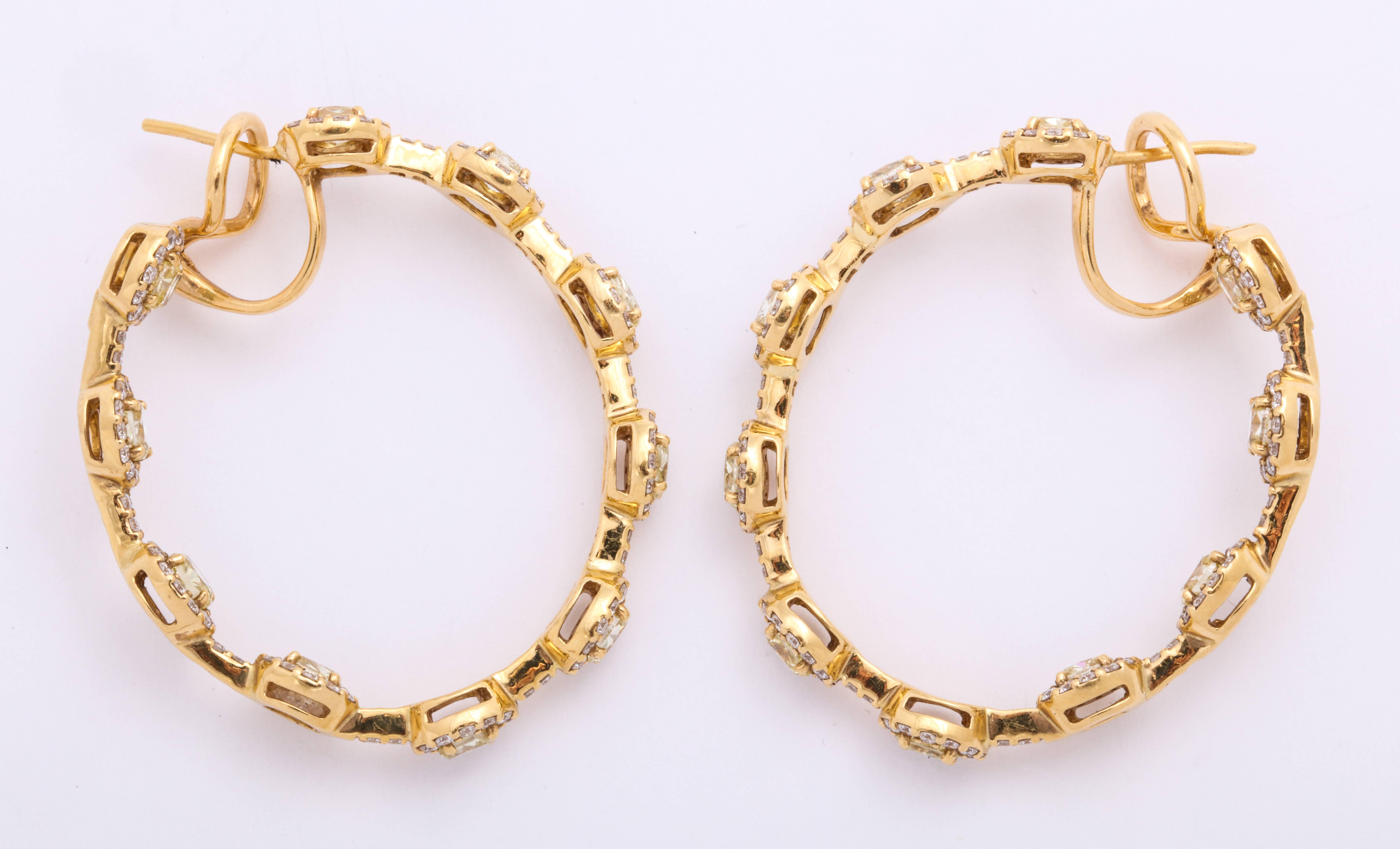 Contemporary stylized 18 Karat yellow gold hoop earrings decorated with colorless round brilliant-cut diamonds: 2.42 carats, mounted with 20 evenly spaced natural color yellow oval diamond stations, total weight: 4.68 carats. For pierced ears with