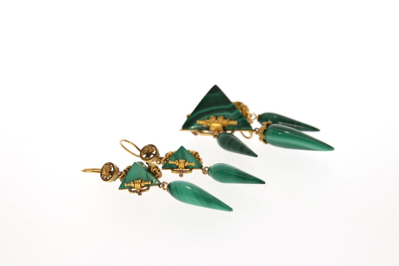 A beautiful antique demi-parure. Comprising a pendant, which can also be worn as a brooch, and a pair of dangle earrings. The refined floral yellow gold setting frames the drop- and pyramid- shaped green Malachites.