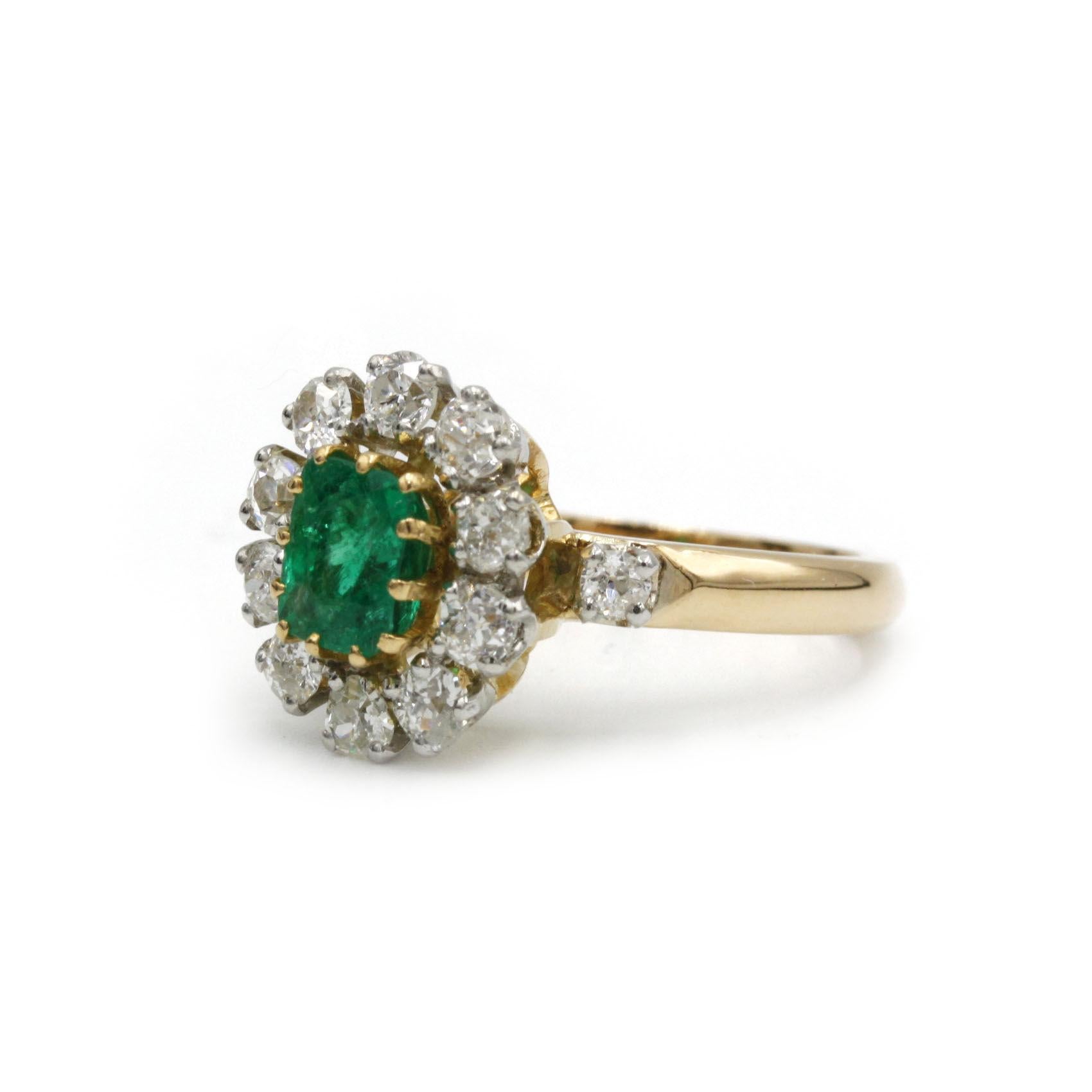 Une charmante bague de style marguerite réalisée en or jaune 18K et platine (950‰), centrée sur une vibrante émeraude taille coussin d'environ 1,10 carats. L'émeraude est encadrée d'un seul halo de dix diamants taille brillant totalisant environ