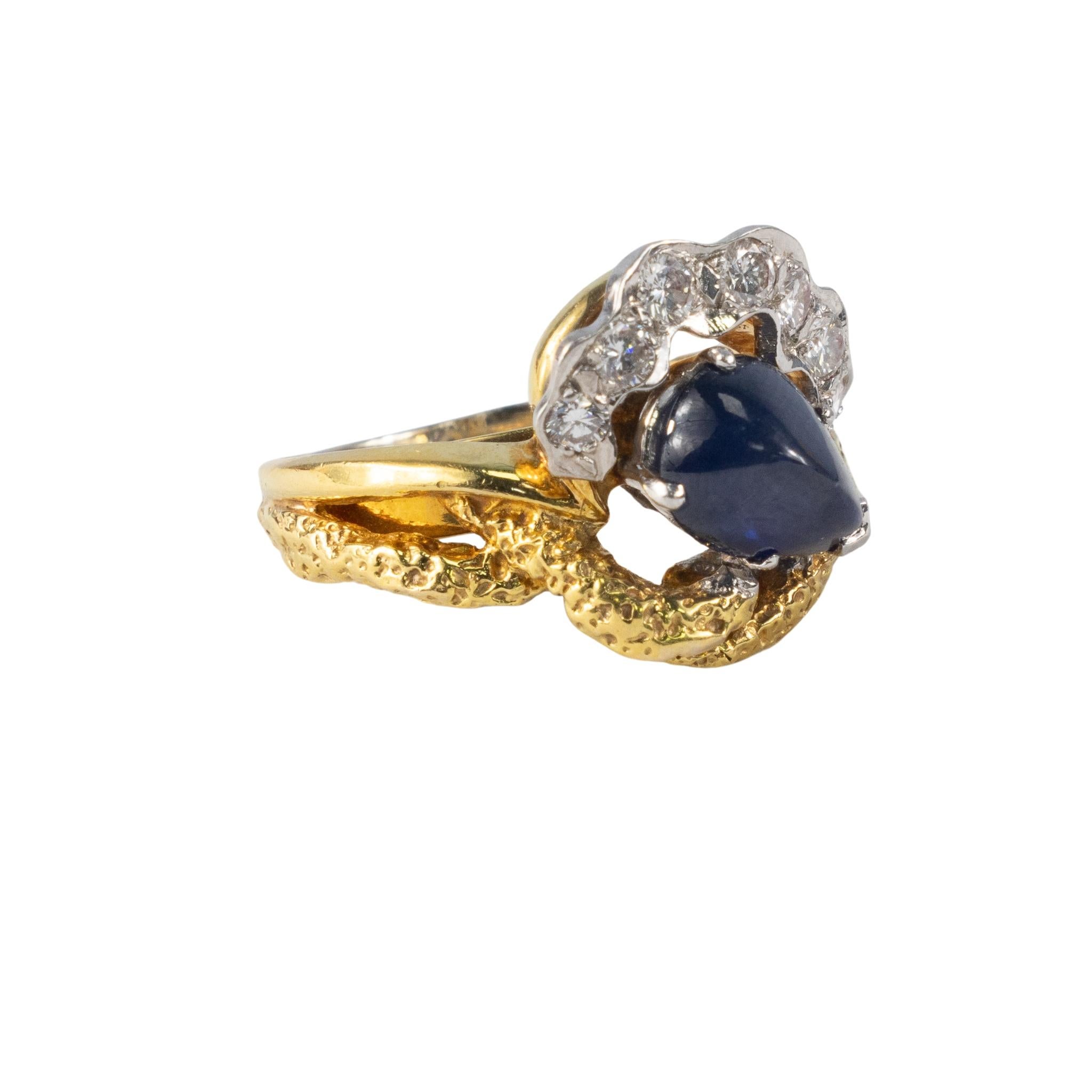 Diamond and Cabochon Sapphire Cocktail Ring

This distinctive 14k white & yellow gold ring features an enchanting pear-shaped cabochon sapphire, elegantly cradled within an organic-textured gold setting. A graceful arc of brilliant round diamonds,